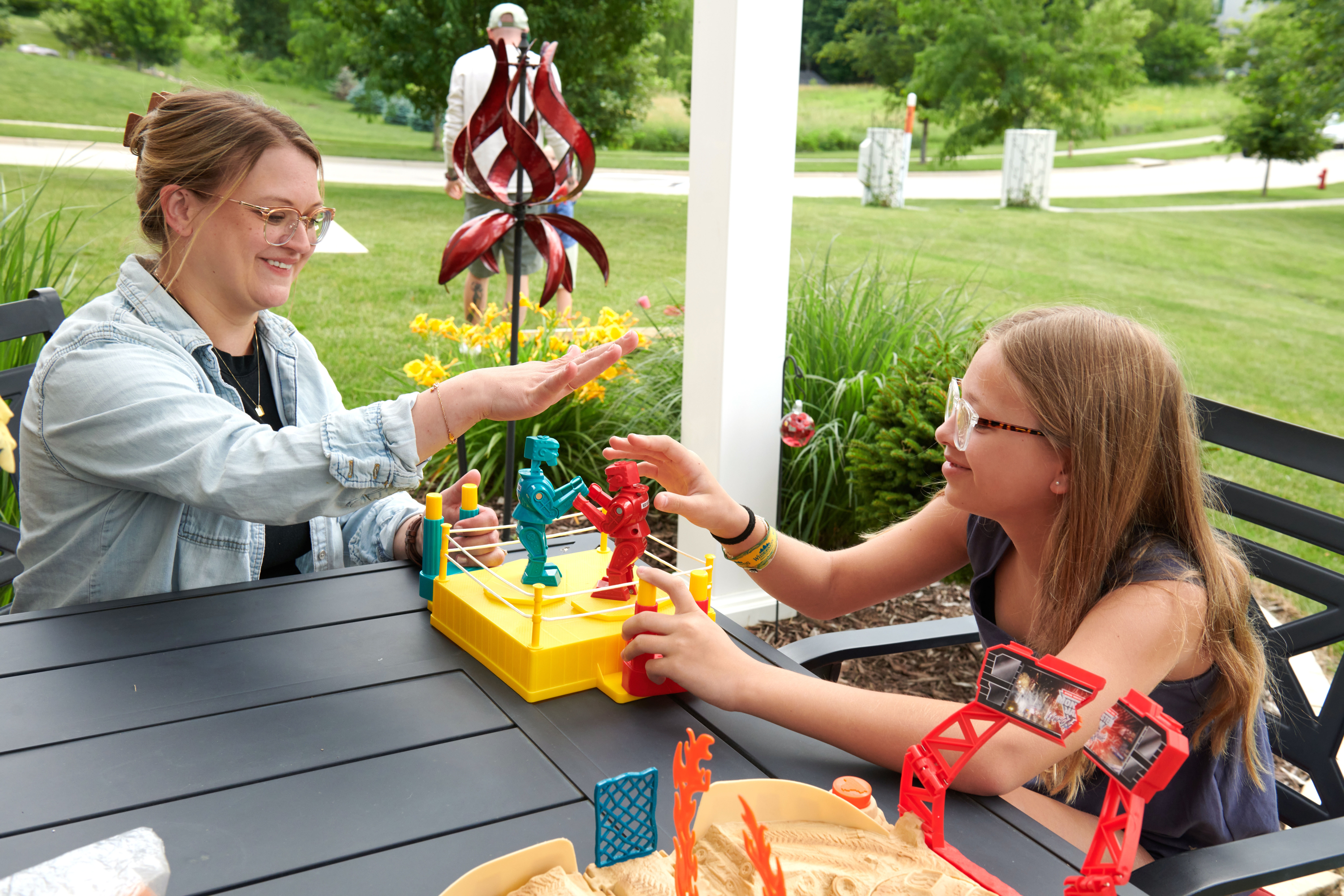 Amber and Piper, 12, play with plastic robots together on a patio.