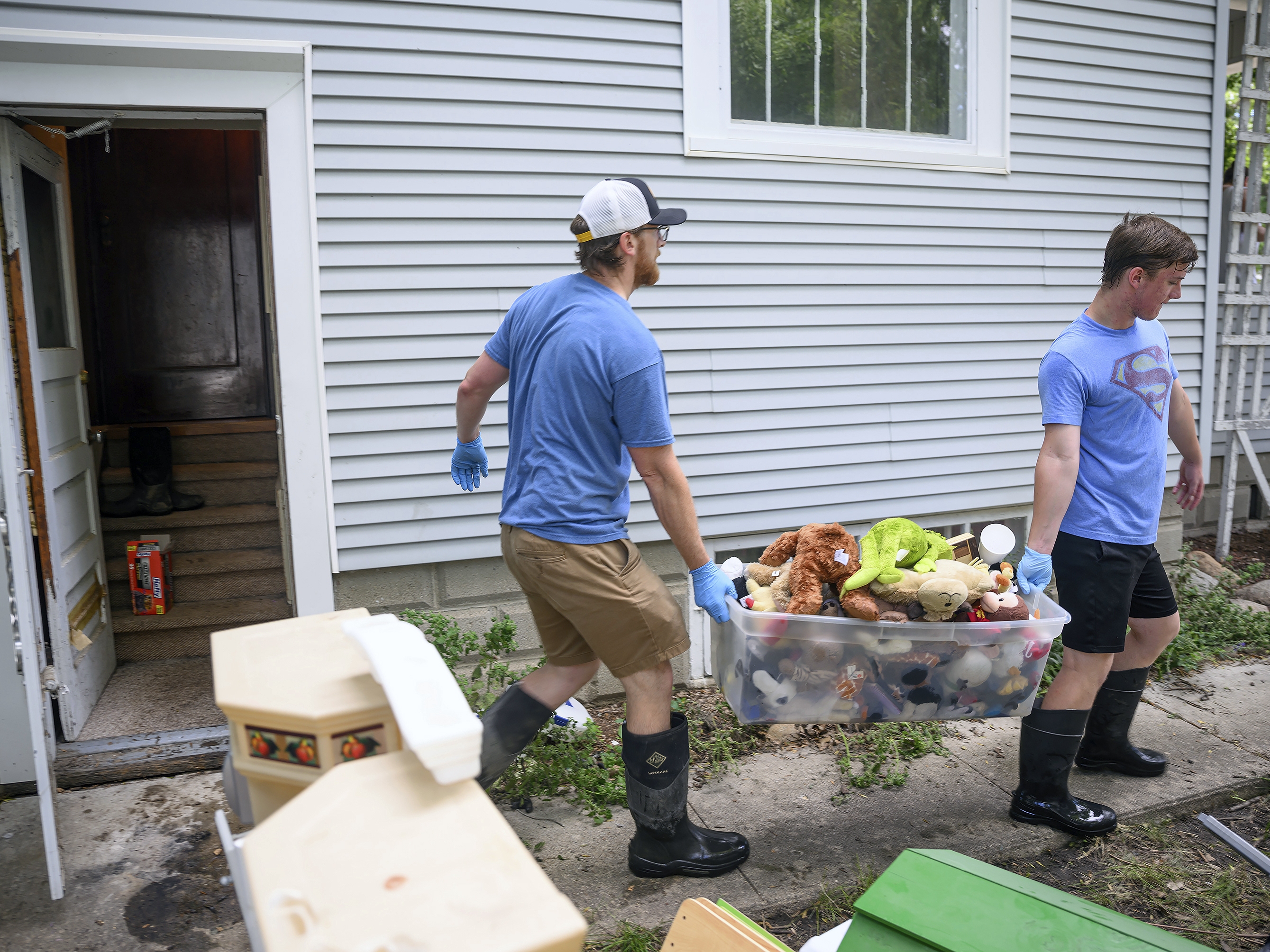 Jared Gerlock (left) and his son, Robbie, carry a bin of water-logged stuffed animals out of the flood-damaged basement of their home on East Second Street in Spencer, Iowa, on Tuesday. Officials said about 40% of properties in the city were affected after the Little Sioux River flooded.