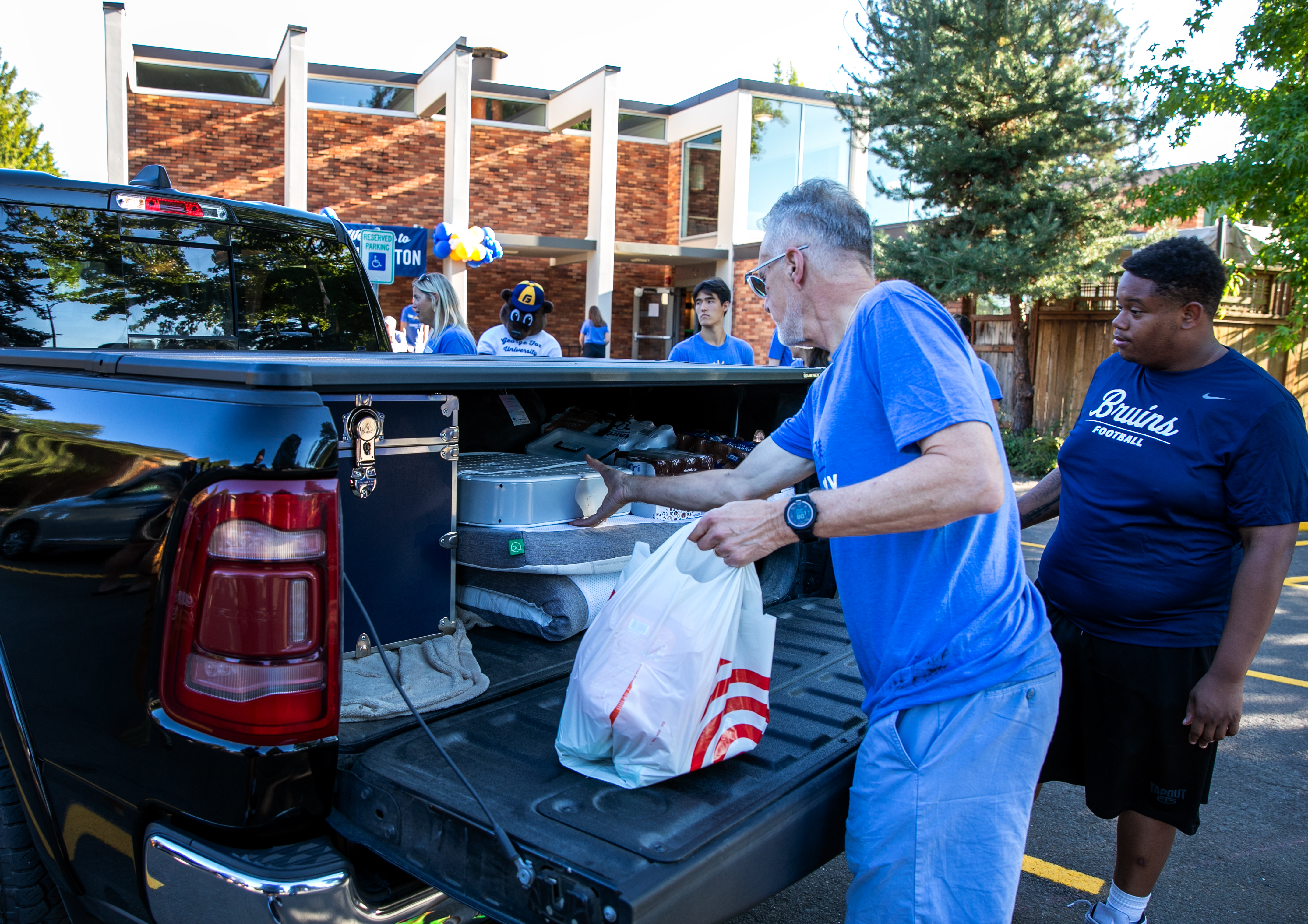 George Fox University President Robin Baker helps unload Rylan Nelson's belongings as Nelson moves into the dorms.
