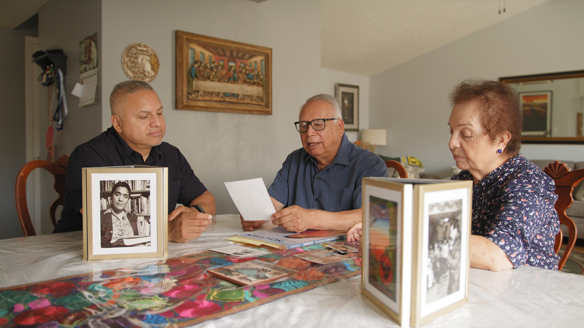 Anthony Veliz (I) Rodolfo Veliz y Candelaria Veliz (D) ojean fotografías familiares de los años del Colegio César Chávez en su hogar en Salem, Oregon el 30 de julio de 2024.