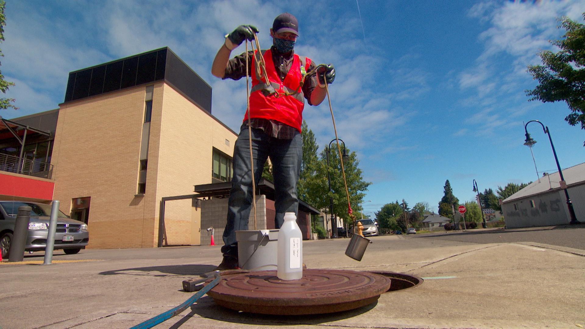 Jason Cook of Clean Water Services pulls a wastewater sample from a sewer in Forest Grove, Oregon. 