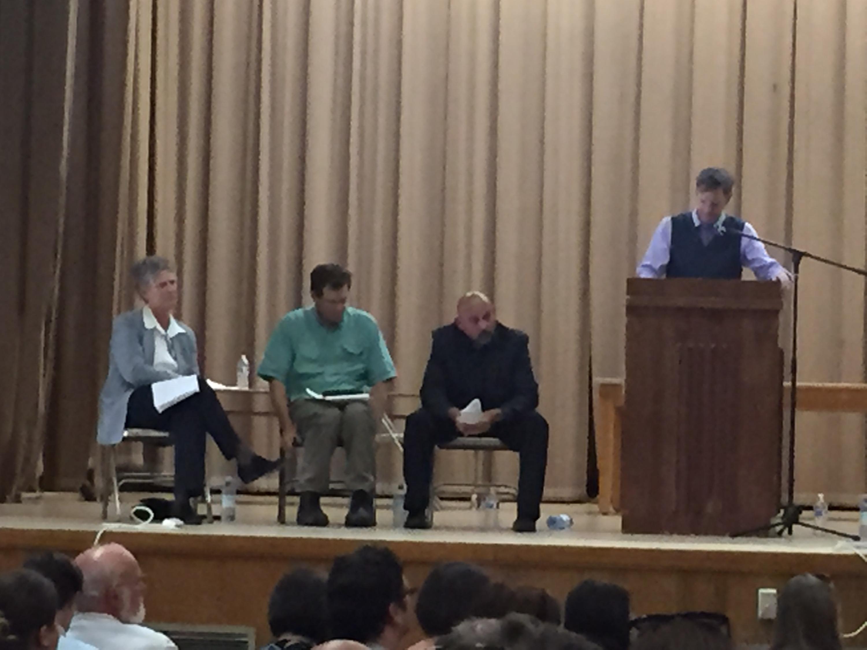 In this May 31, 2016 photo, Portland officials listen as parents voice objections to recent revelations of lead found in school drinking water. From left, Superintendent Carole Smith, Portland Public Schools Board of Directors Chair Tom Koehler, PPS Chief Operating Officer Tony Magliano and Portland-area State Representative Rob Nosse (standing).