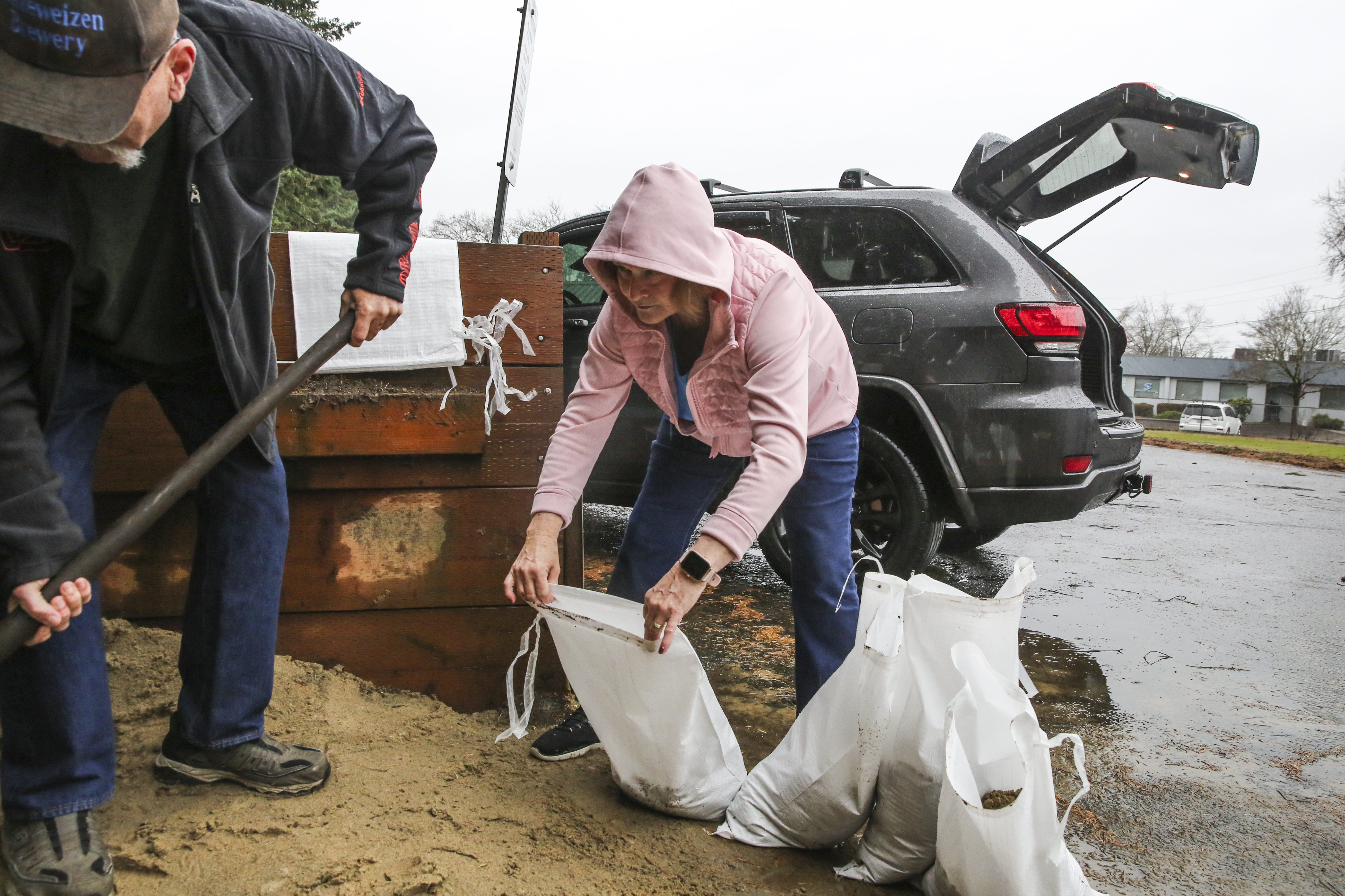 Bill and Denise Lakey fill sandbags at the Clackamas Fire Station in Milwaukie. They live next to a steep road that funnels water down their driveway and into their garage. Dec. 18, 2025