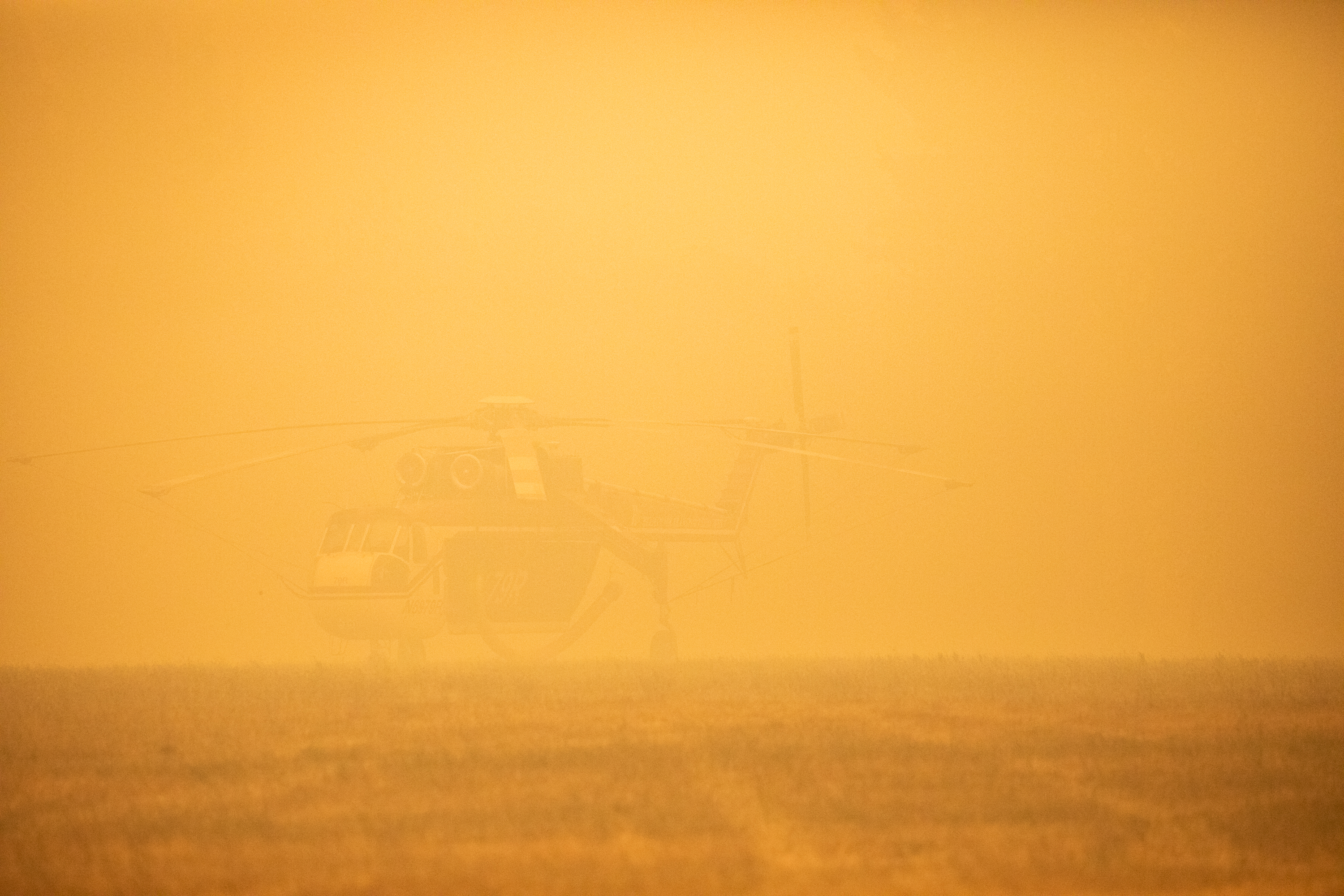 A helicopter is grounded in a smoky field near the incident command center for the Santiam Fire near Gates, Ore., Sept. 9, 2020. Fire, wind and road conditions have been so bad they've slowed search and rescue efforts in the canyon.