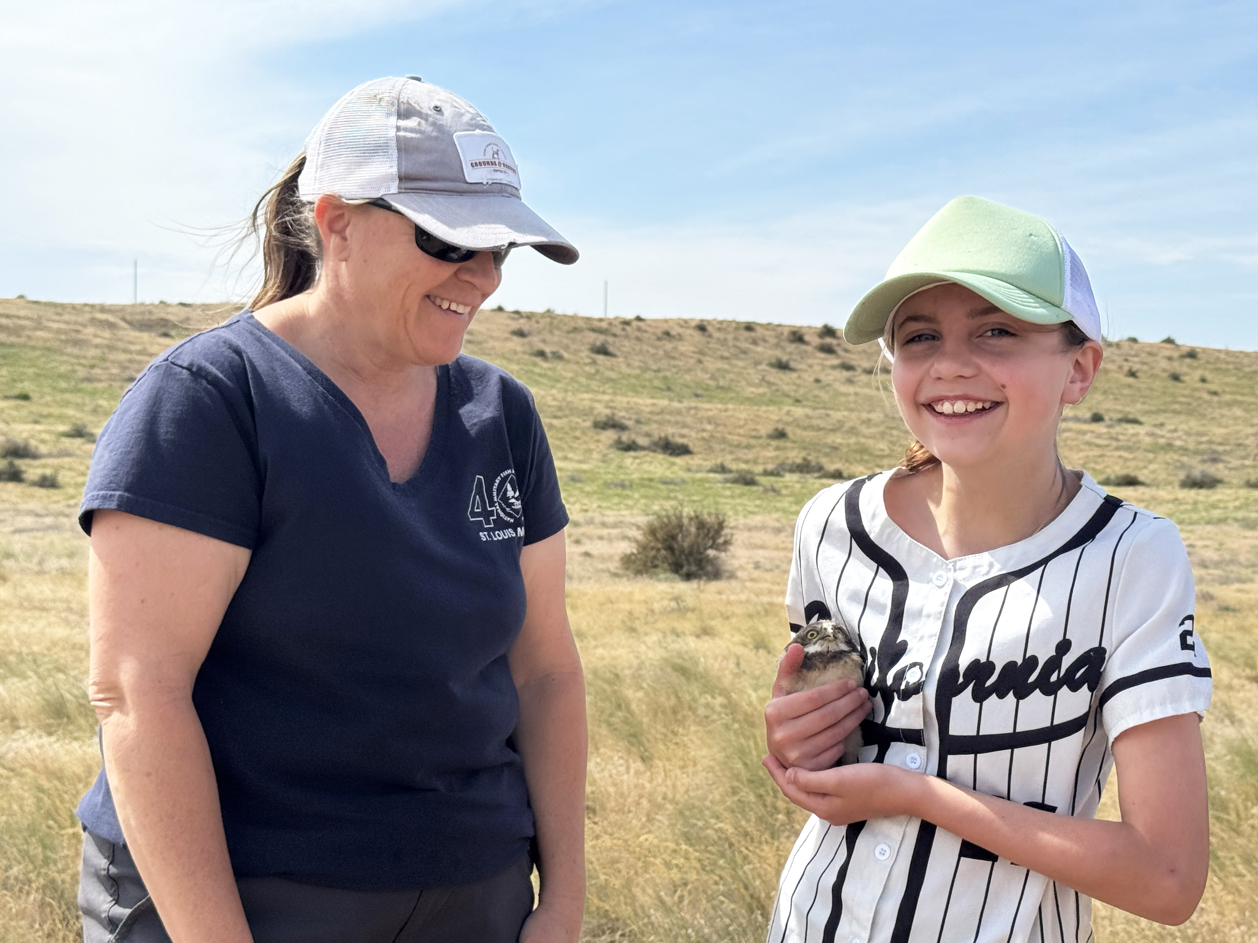 Judy Johnson, left, helps 11-year-old Gabby Chase hold a baby burrowing owl on property managed by the Confederated Tribes of the Umatilla Indian Reservation. Volunteers helped researchers band the baby owls so that the birds can be tracked throughout their lifetimes.