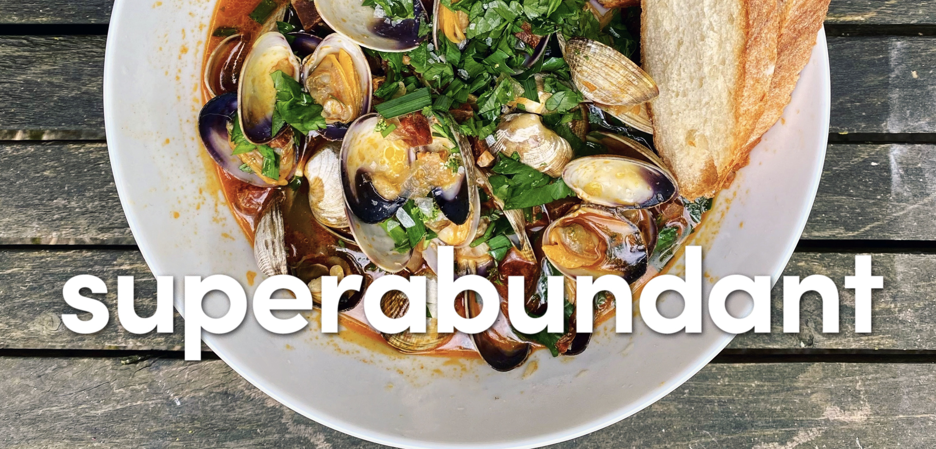 A bowl of clams in broth with chopped herbs and bread