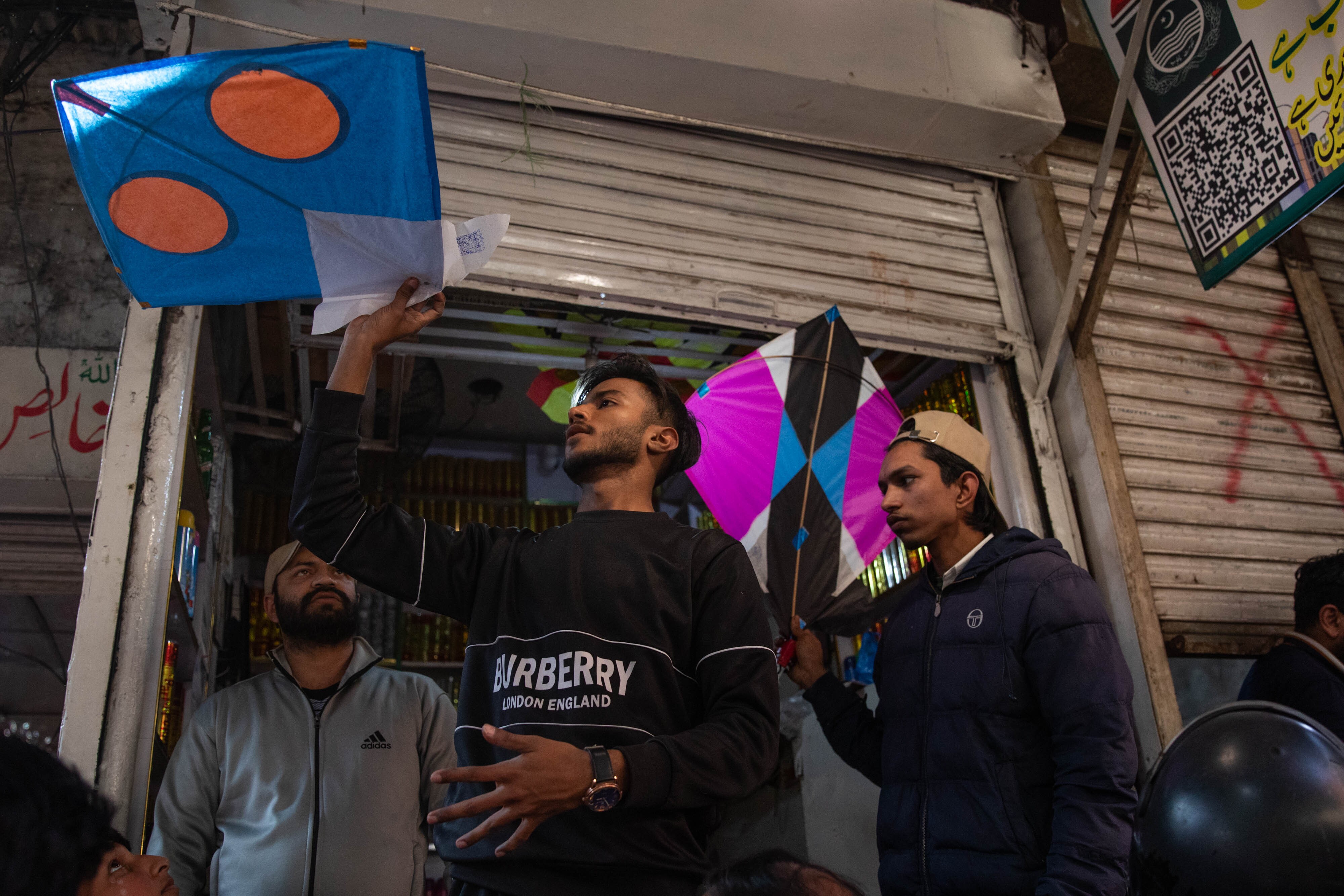 Vendors hold colorful kites in a market area near Mochi Gate ahead of the springtime festival Basant in Lahore, Pakistan. A QR code is visible on one kite, designating that the vendor was registered with the government and allowed to sell.
