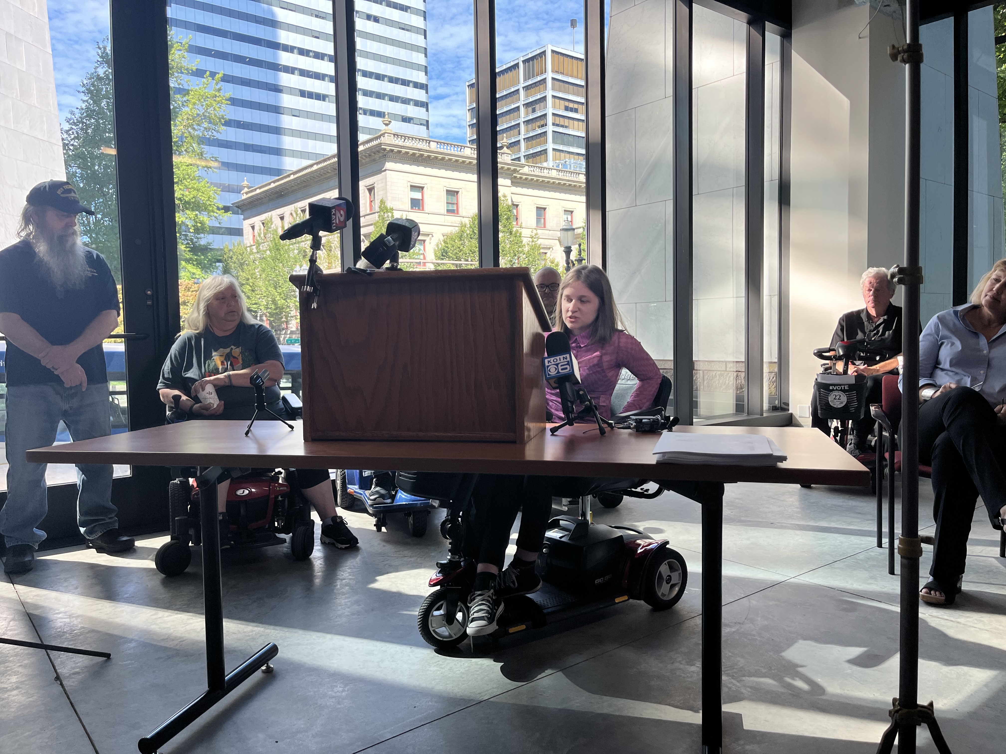 A young woman in a wheelchair approaches a podium to speak.