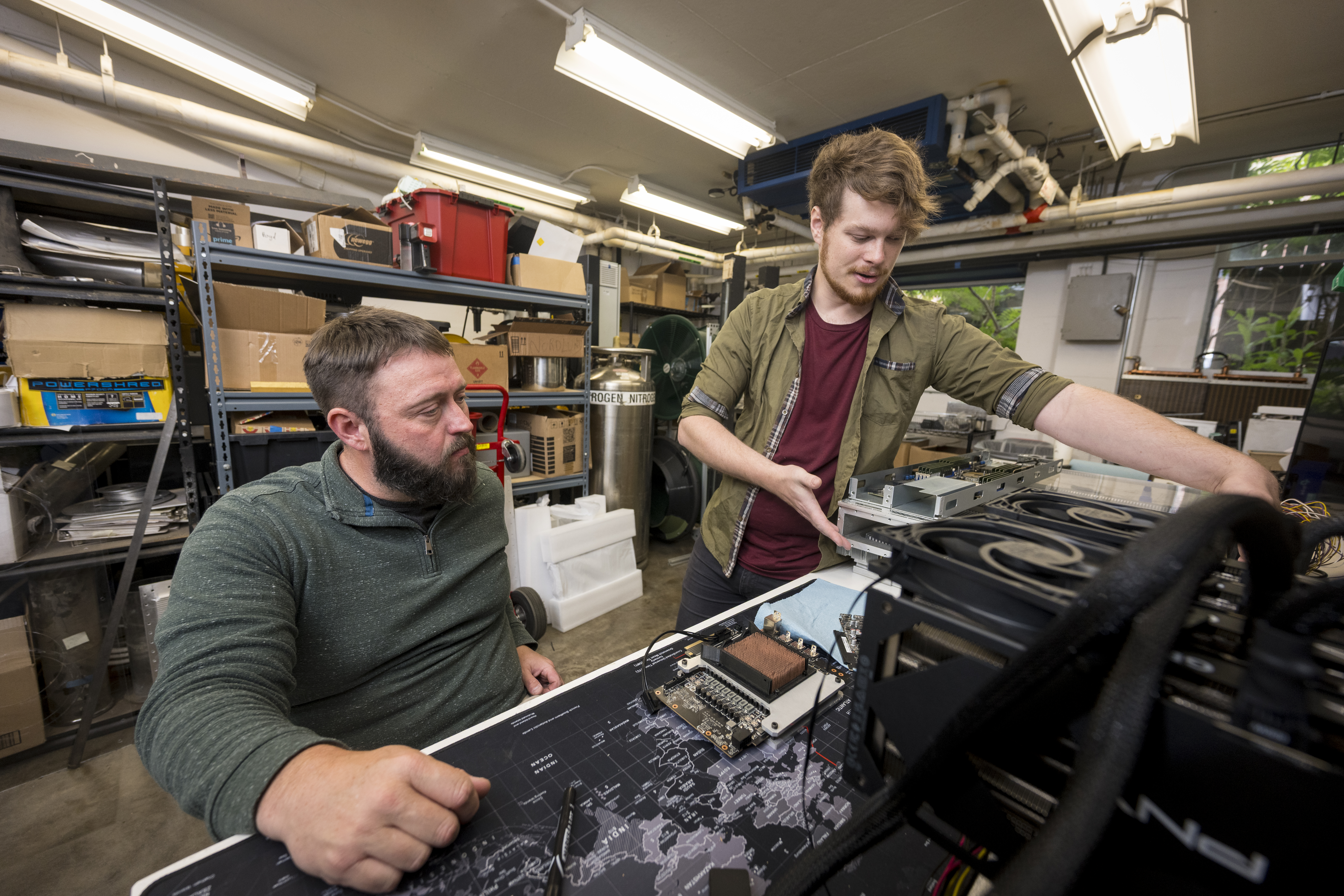 In this provided photo taken in June 2025, Oregon State University engineering professor Josh Gess (left) and faculty research associate Alec Nordlund (right) work on a system to cool servers by immersing them in dielectric oil.