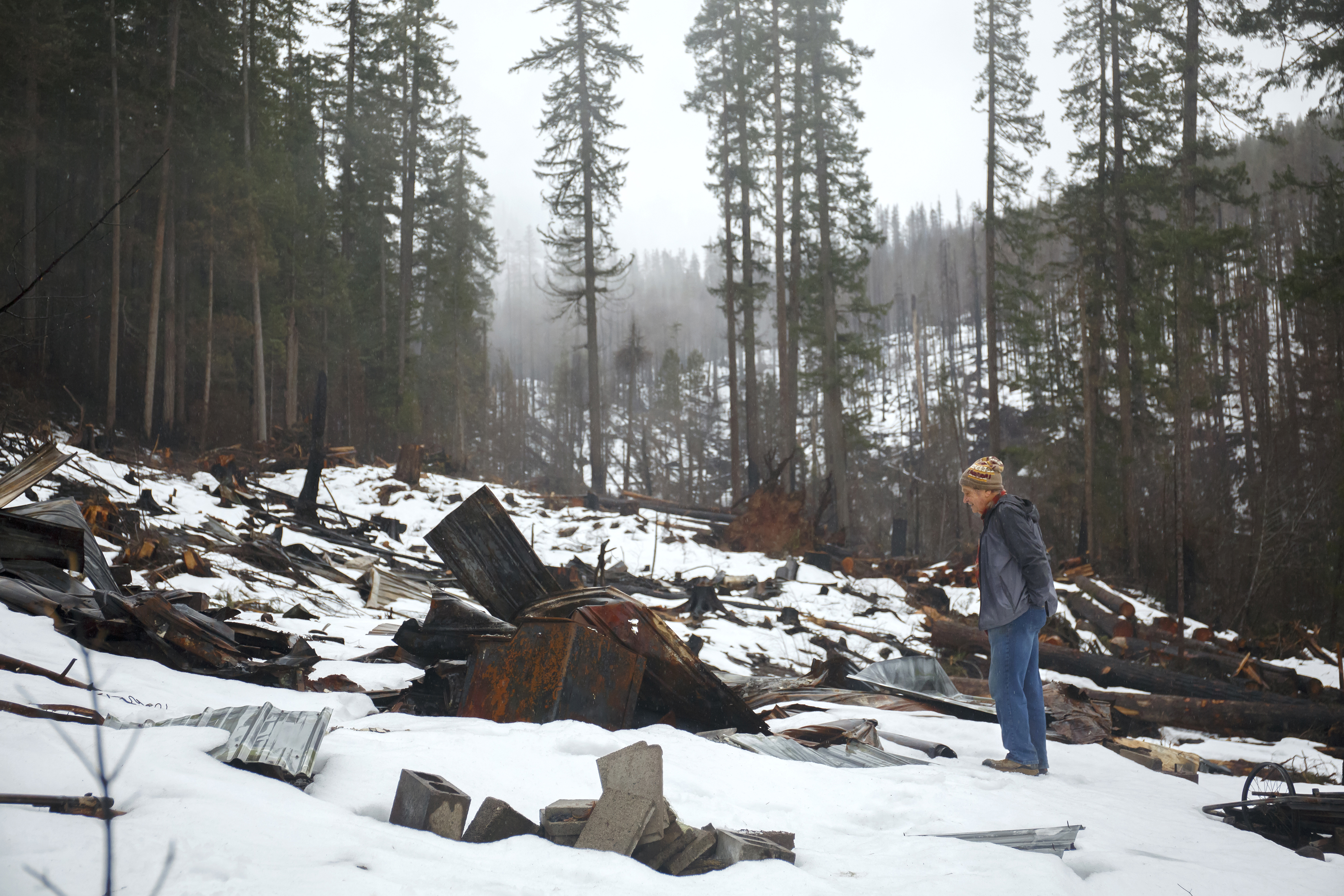 Jay Hennigan, president of the Breitenbush Cabin Owners Association, looks at some of the rubble remaining where his cabin once stood in Breitenbush, March 5, 2021. The cabin was destroyed by the Beachie Creek and Lionshead fires in 2020. 