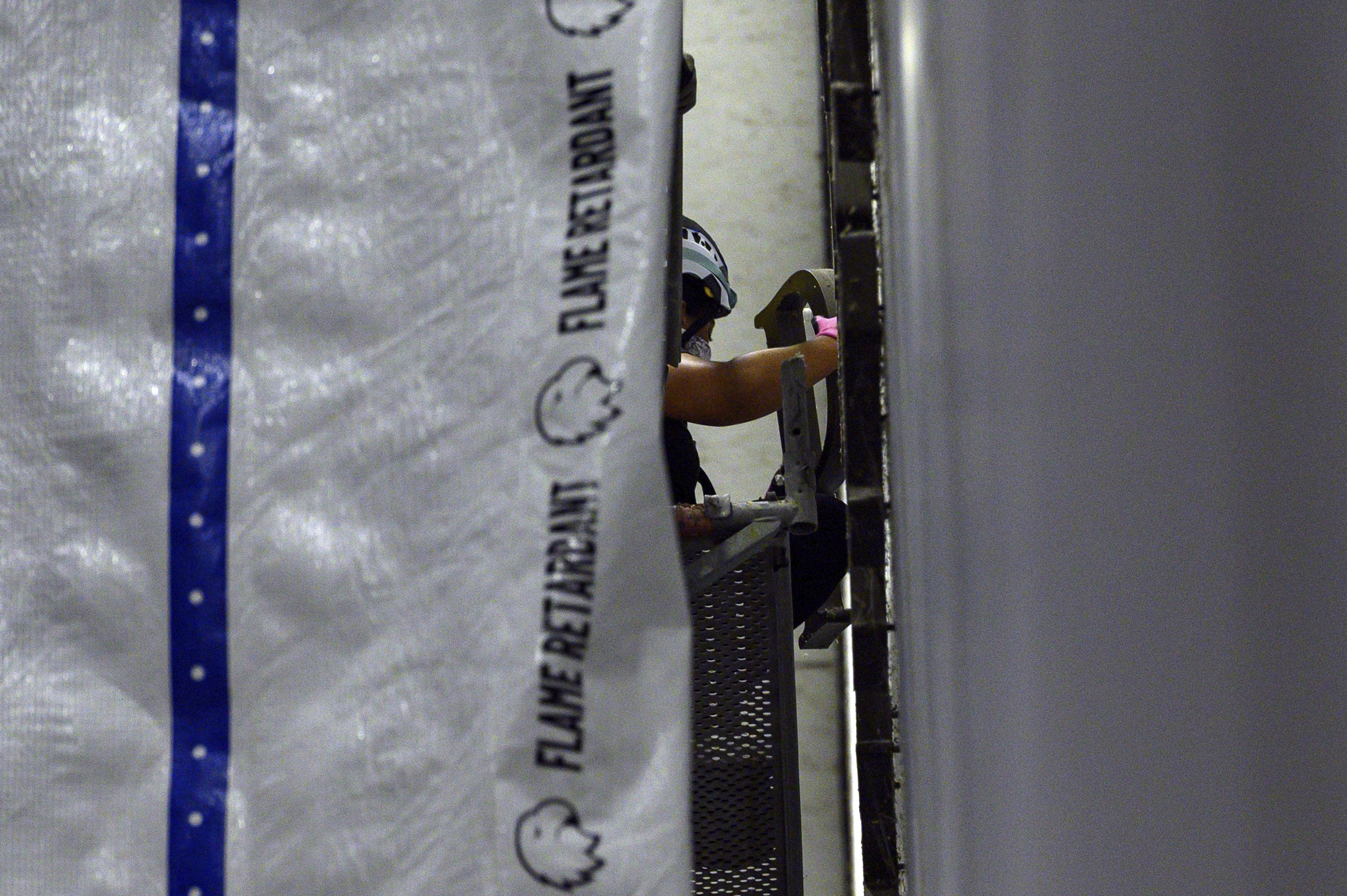 A worker removes a letter from President Donald Trump's name from the wall of the John F. Kennedy Center for the Performing Arts in Washington, Saturday, June 13, 2026.
