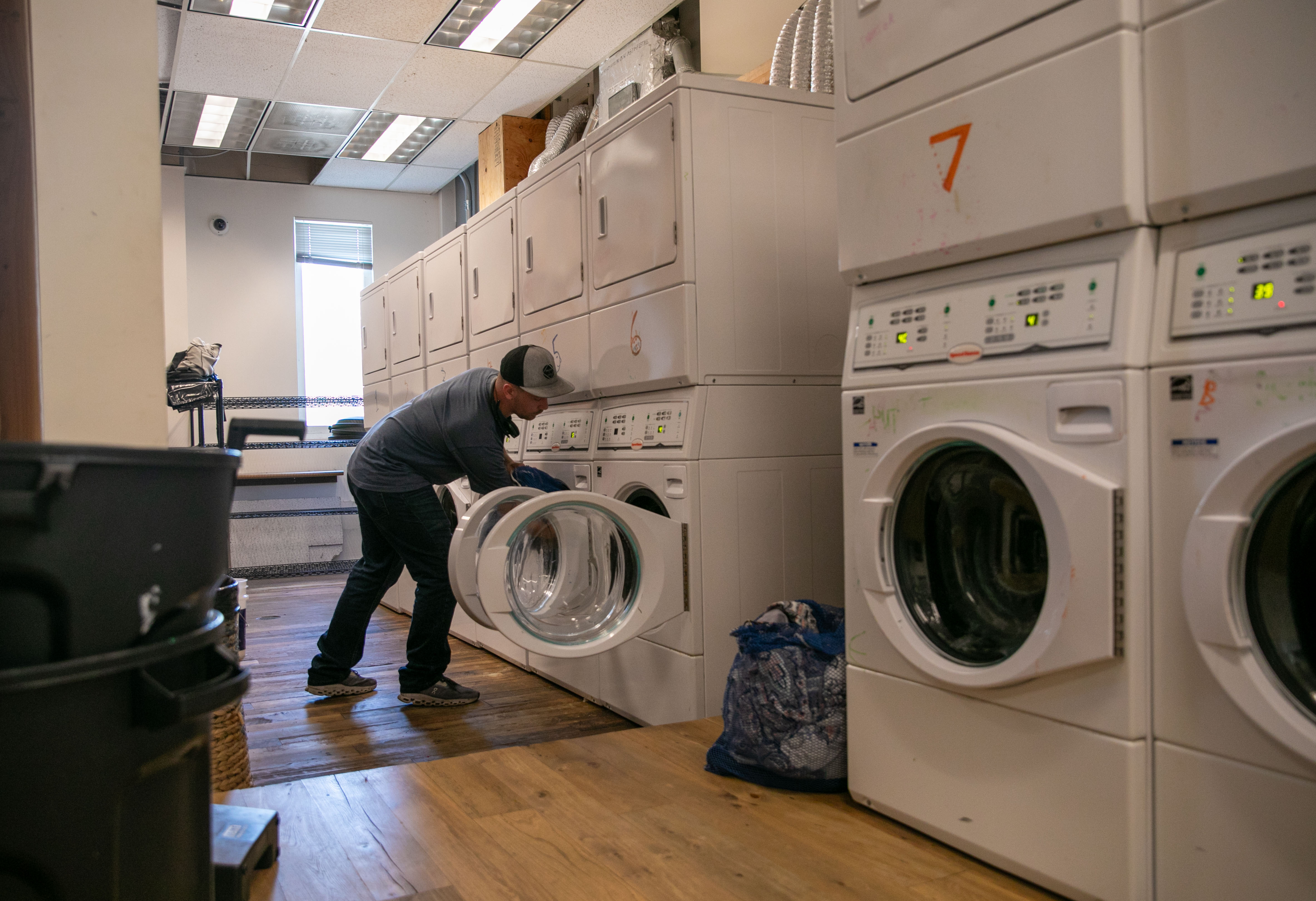 Wash House employee Mack Johnson loads laundry into a washing machine in Portland, Ore., July 22, 2025. The Wash House is part of the Portland City Laundry Program, providing a place for houseless individuals to get their laundry cleaned as needed. 