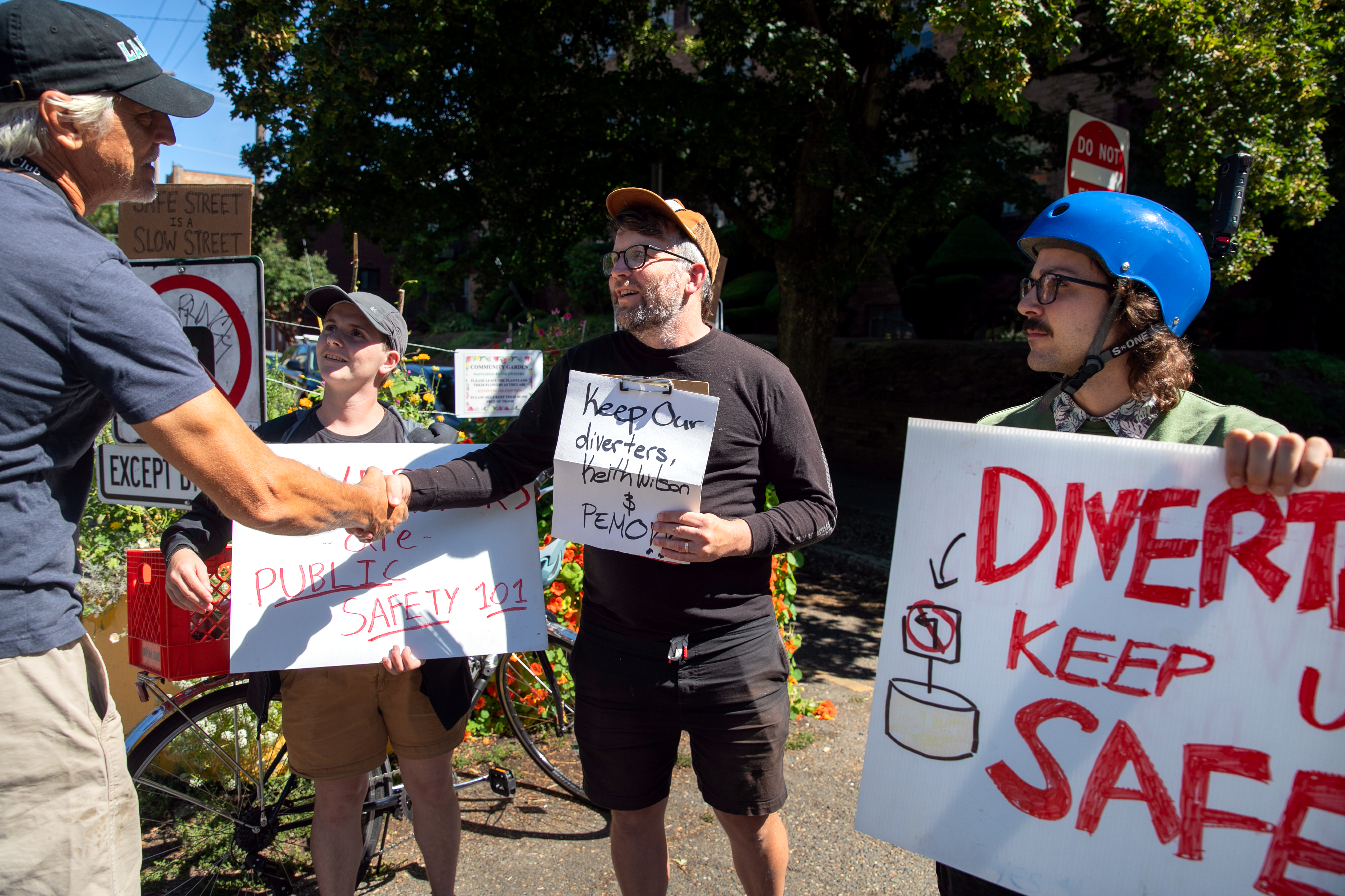 (Left to right) Protesters Connor Lennon, Sven Gunvalson and Nick Levin shake the hands with a person after discussing the importance of traffic diverters to the local community in Portland, Ore., Aug. 9, 2025. Multiple Portlanders chose to protest this diverter removal for the sake of civilian safety, some of which even arriving at the scene as early as 6 a.m.