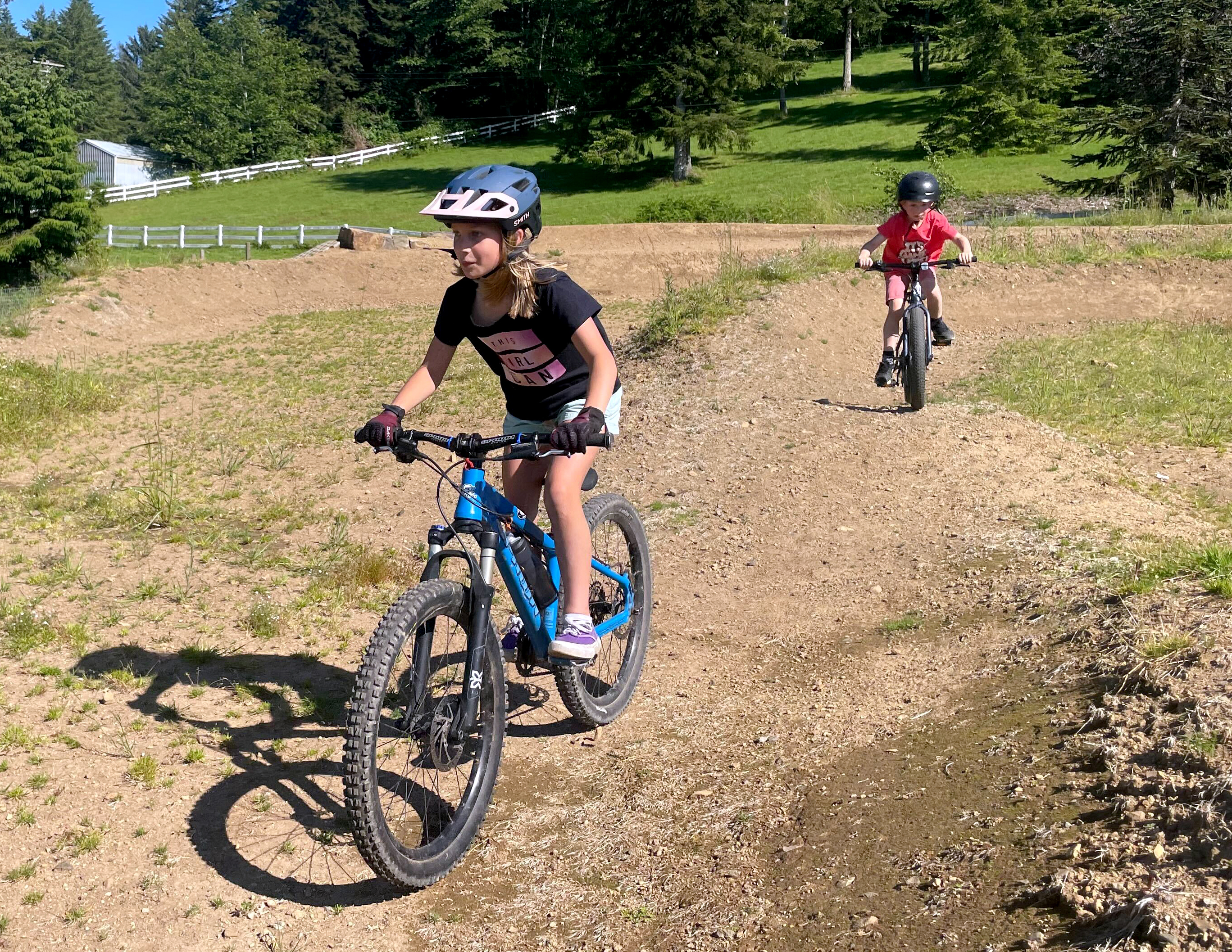 Eleanor Baker, left, and Taj Fields, right, ride mountain bikes on June 7, 2024, behind the Nestucca K-8 School, which is part of the local school district in southern Tillamook County near Cloverdale. Supporters of a proposed nearby mountain biking system hope it will help connect young people with nature.