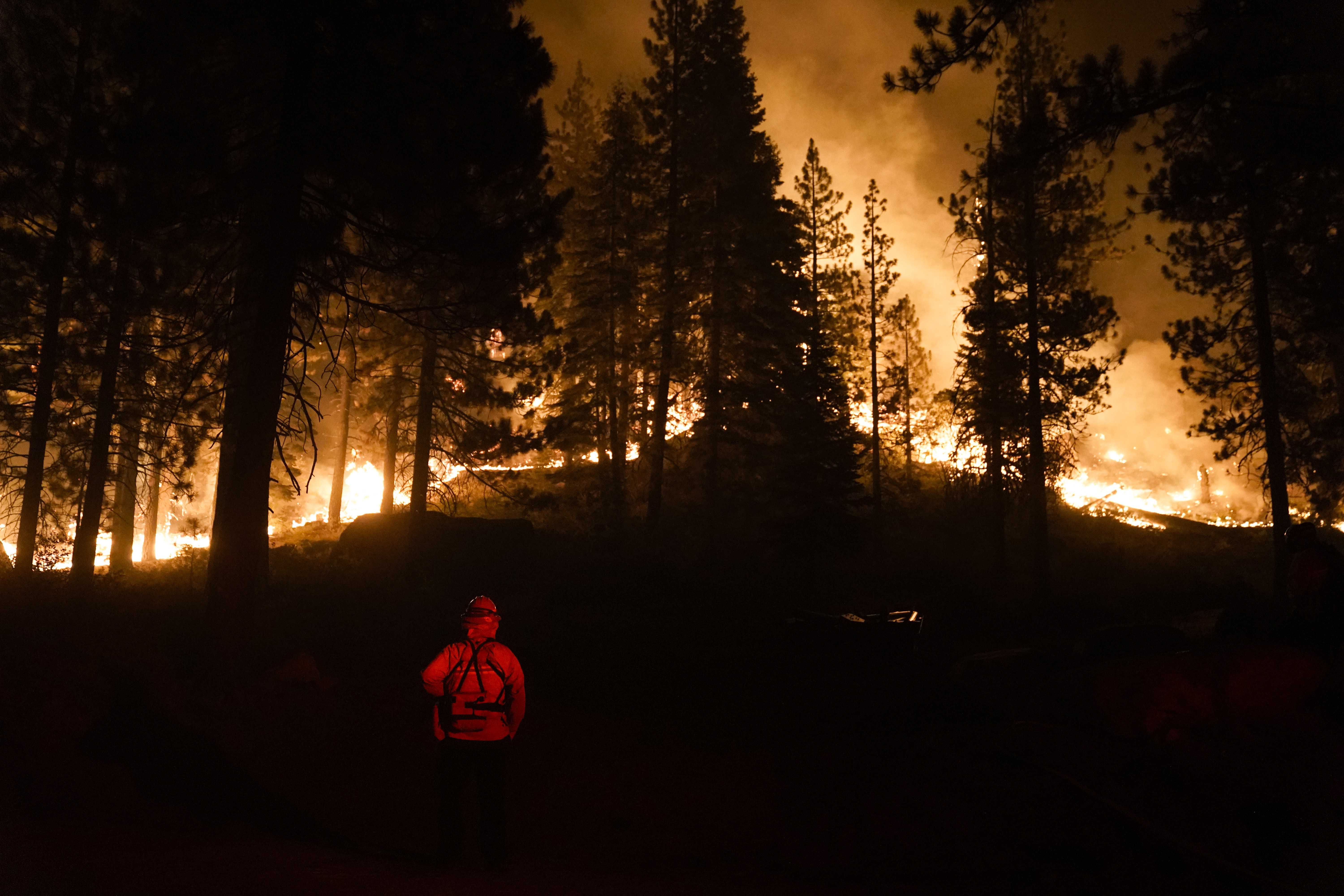 A firefighter monitors the Caldor Fire burning near structures in South Lake Tahoe, Calif., Monday, Aug. 30, 2021. As the winds returned this week, the Caldor Fire roared over the Sierra crest and bore down on the southern end of Lake Tahoe. (AP Photo/Jae C. Hong)