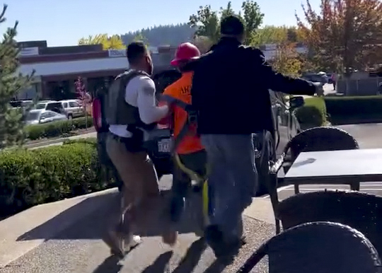 In a screenshot of a video provided to OPB, federal immigration officers apprehend a construction worker near Mall 205 in Portland, Ore., on Oct. 15, 2025. This screenshot was provided to OPB by a witness who asked not to be identified out of fear of repercussions.
