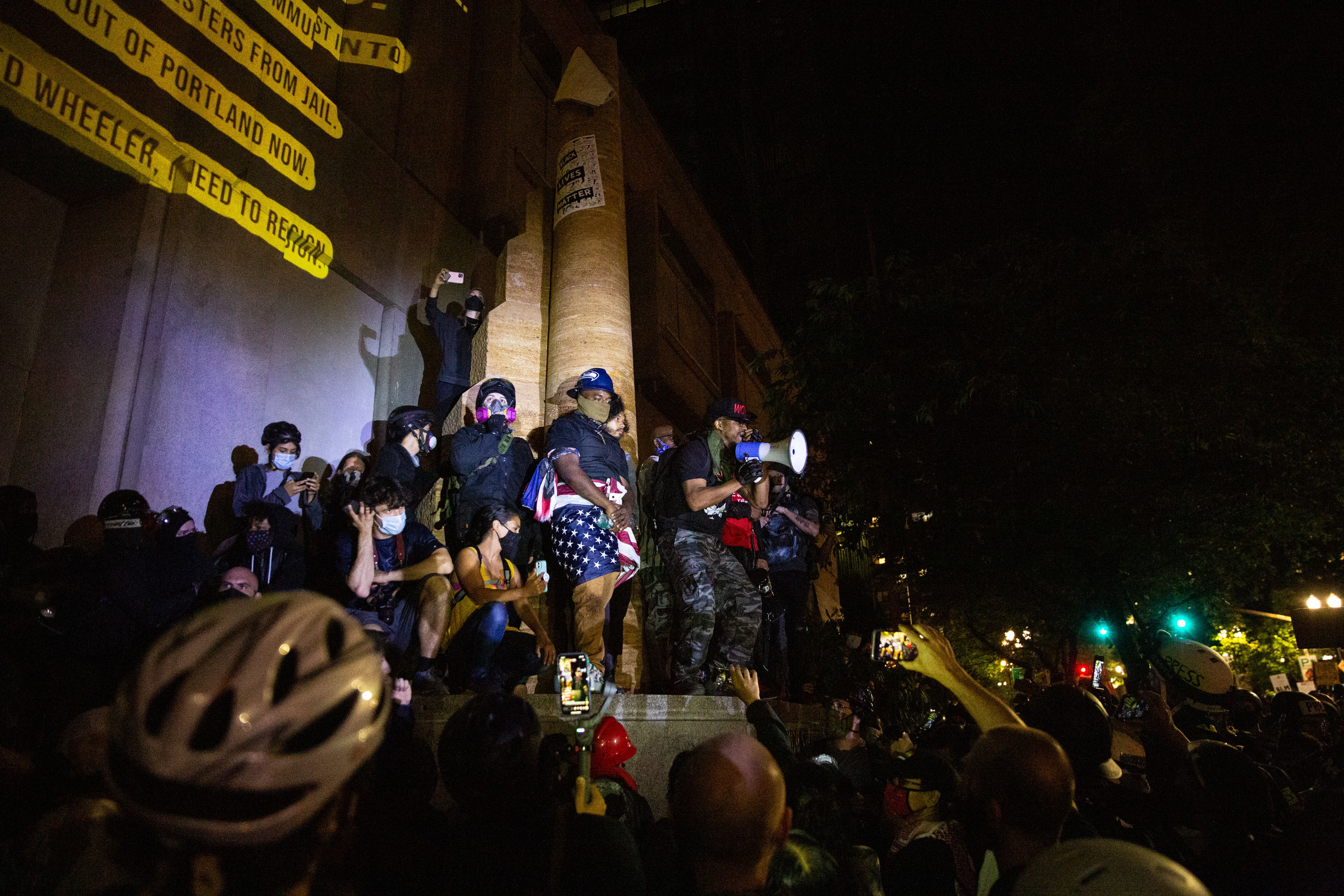 Mac Smiff (with megaphone) speaks to a crowd gathered at the Multnomah County Justice Center in Portland, Ore., July 22, 2020.