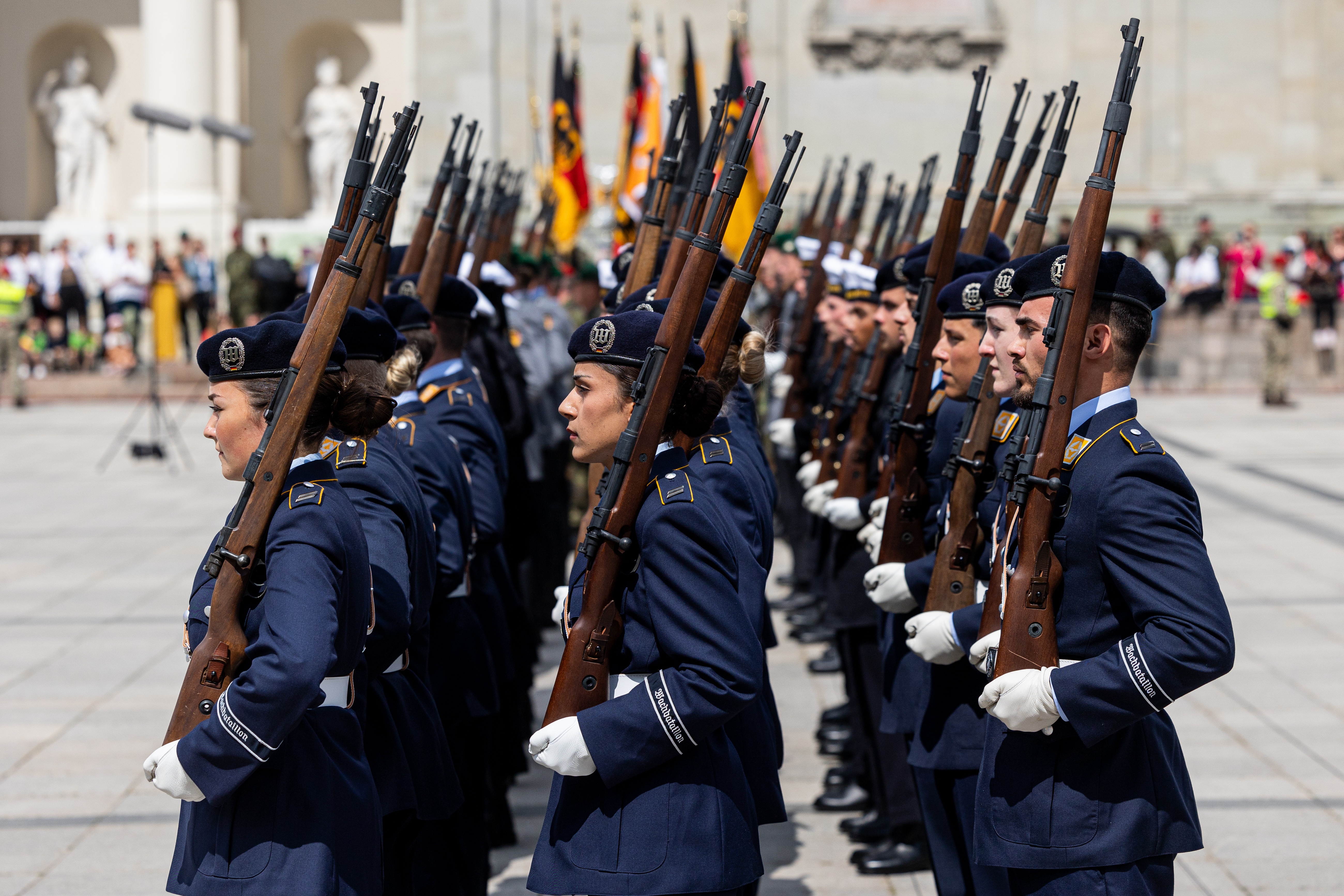 German soldiers wearing navy blue uniforms and carrying rifles stand in three rows during a ceremonial roll call on May 22, 2025, in Vilnius, Lithuania.