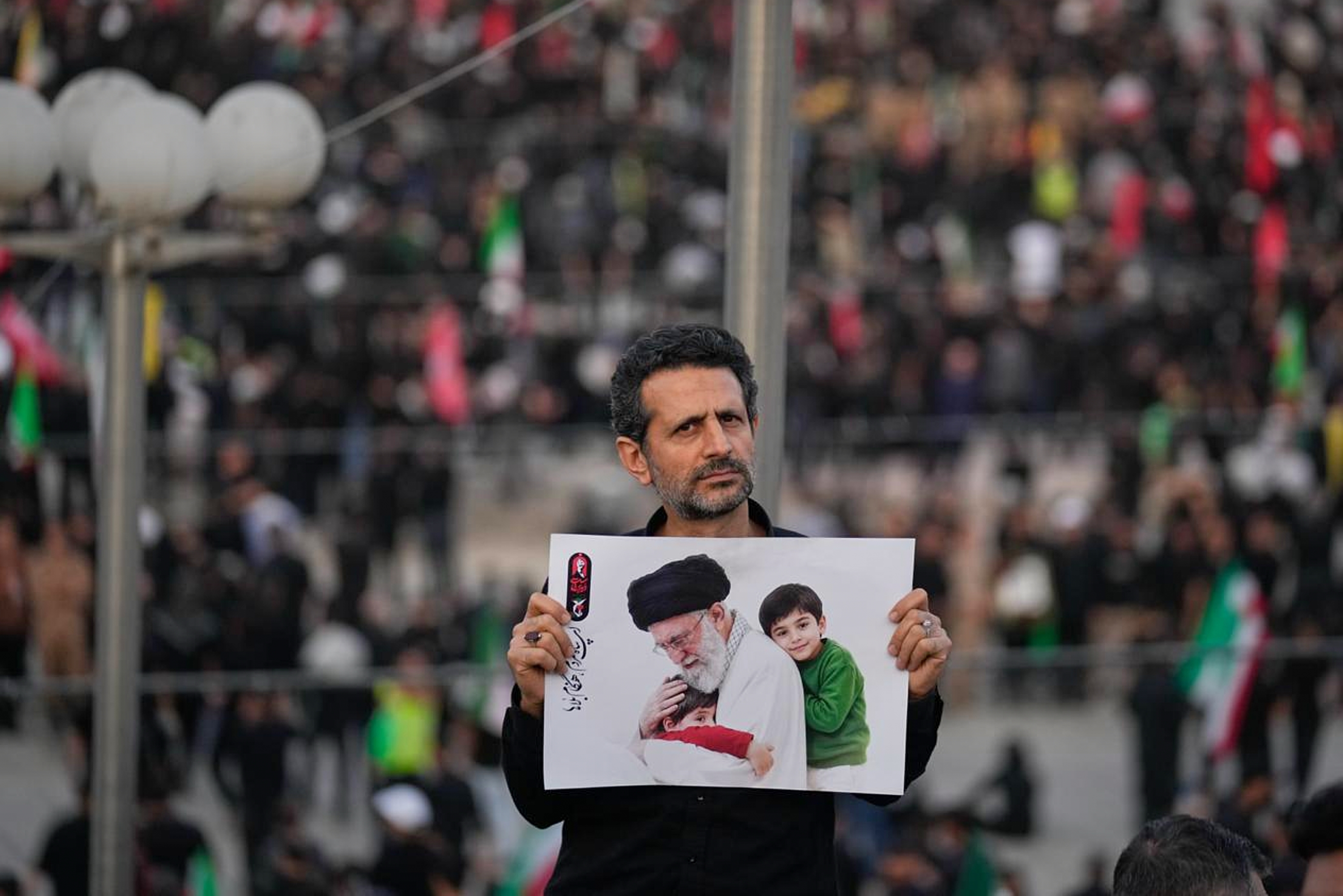 A man holds a picture of slain Iranian Supreme Leader Ayatollah Ali Khamenei as a crowd waits for his casket to arrive at the Imam Khomeini Mosalla Grand Mosque for the start of the dayslong funeral ceremonies in Tehran, Iran, Saturday, July 4, 2026.