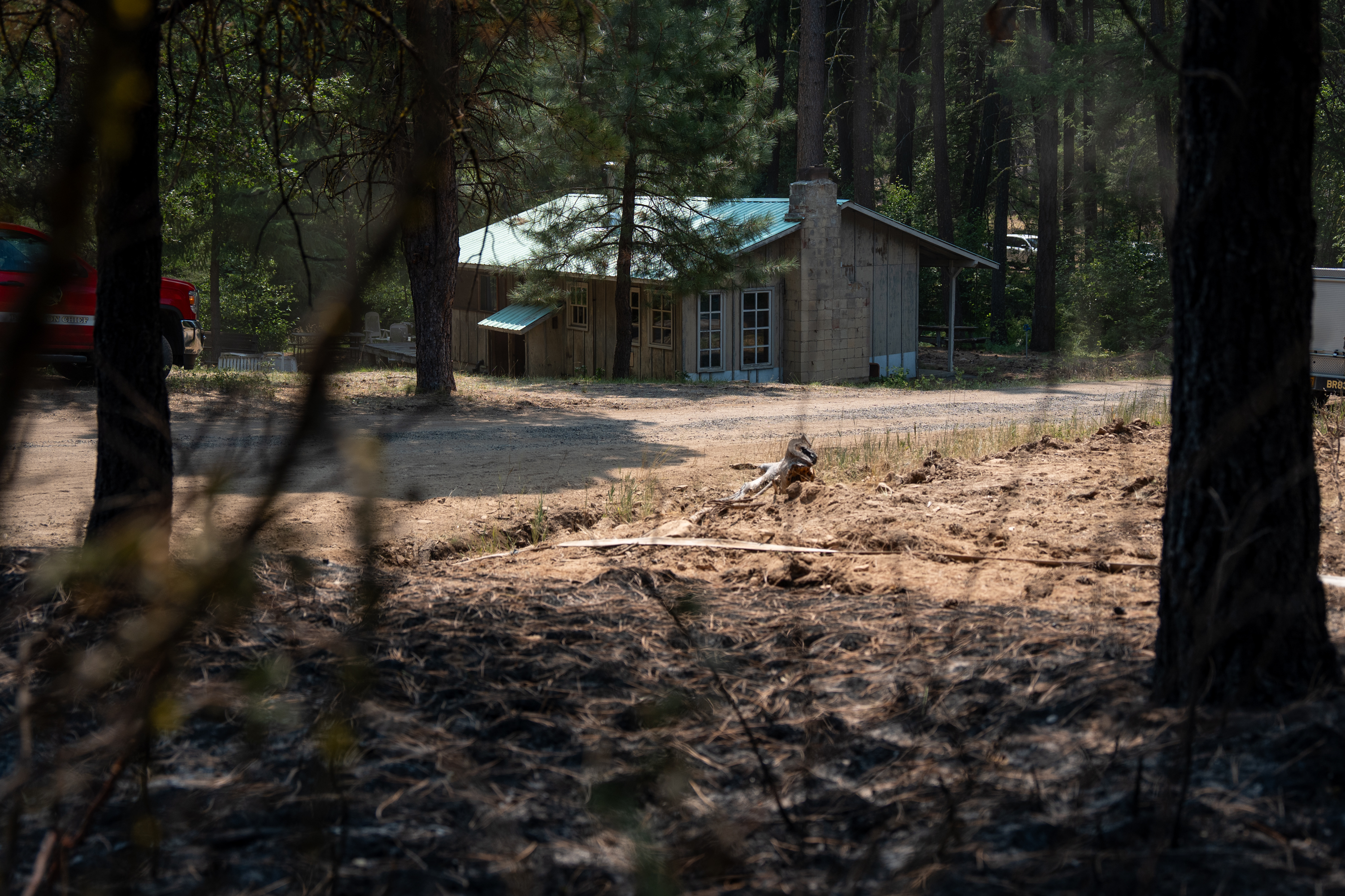 A bulldozer line protects a property just beyond charred trees and dirt burnt in the Grasshopper Fire in the unincorporated community of Sportsman Park, Ore.