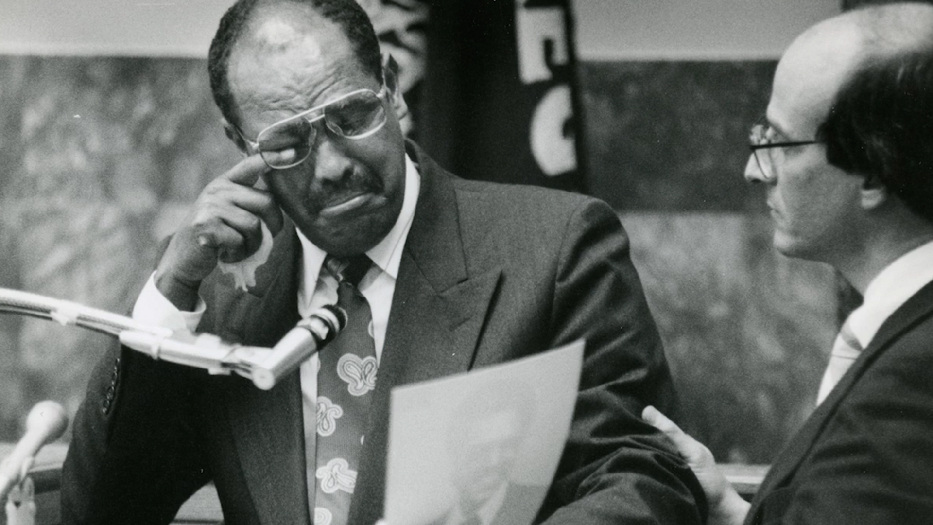 Engedaw Berhanu, Mulugeta Seraw's uncle, testifies at the civil trial against the white supremacist Tom Metzger in 1990. Co-counsel Elden Rosenthal shows a photograph of Mulugeta Seraw as Berhanu wipes tears from his eye.