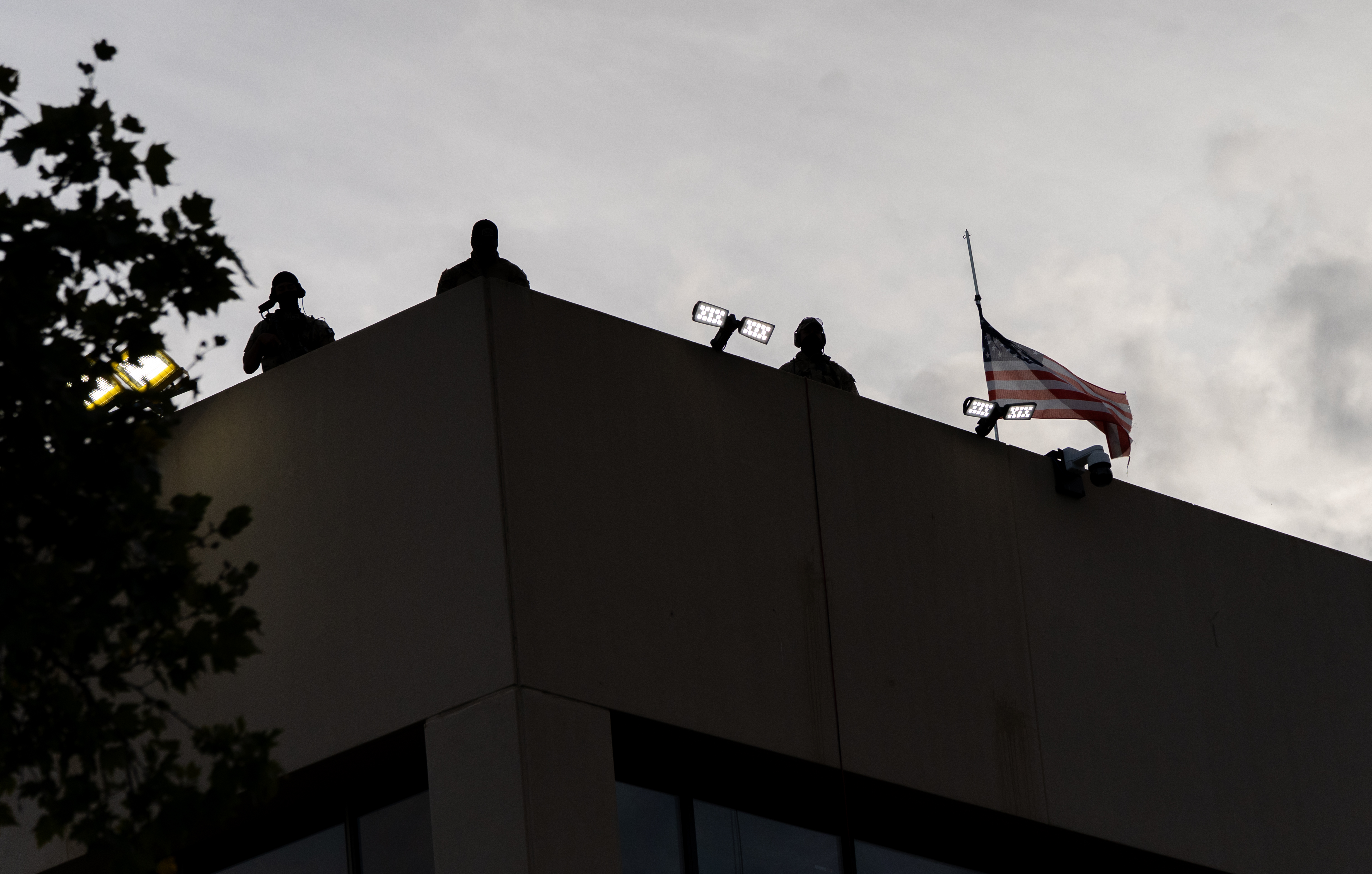 Federal agents keep watch from atop the U.S. Immigration and Customs Enforcement facility in Portland, Ore., on Sept. 28, 2025.
