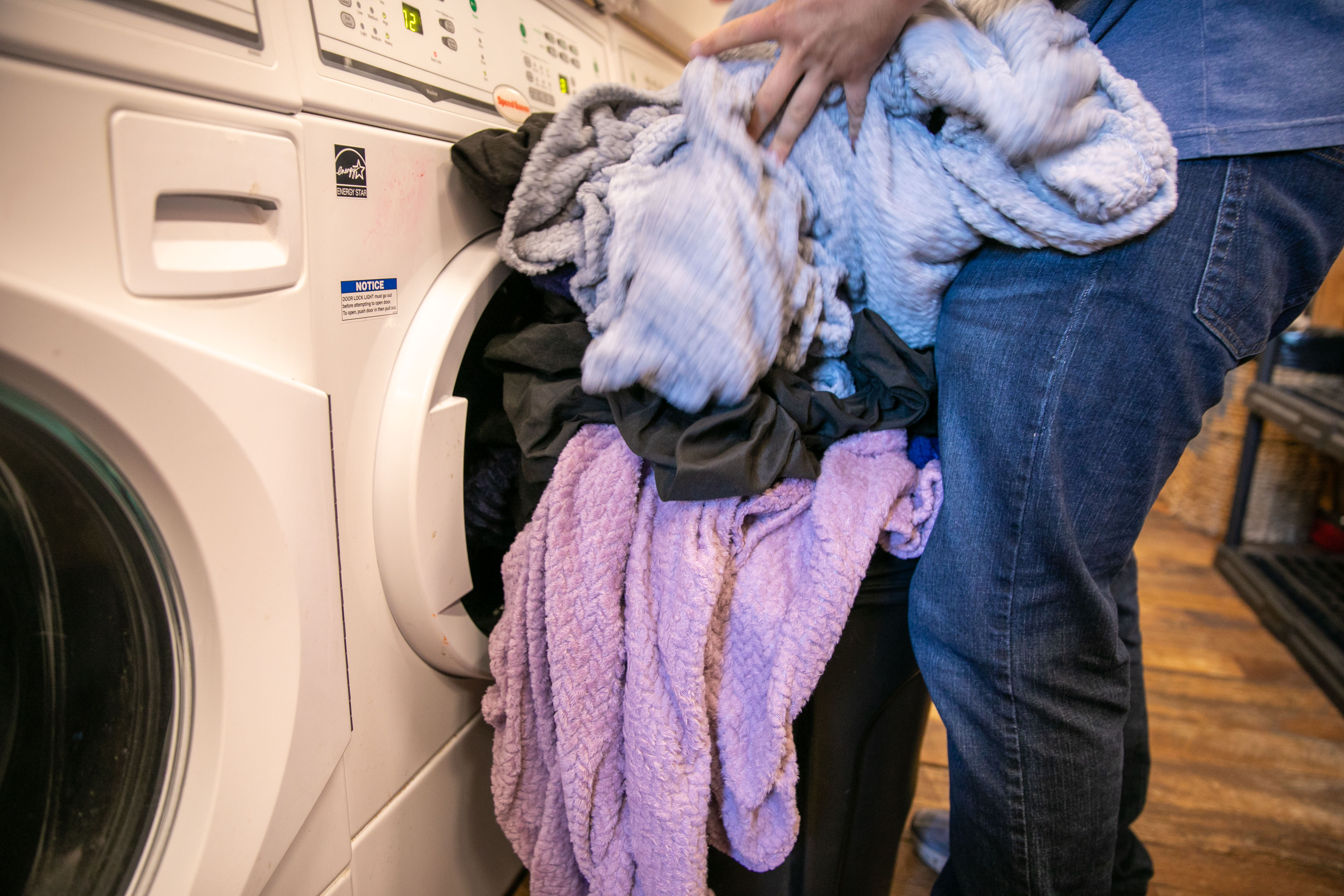 Wash House employee Mack Johnson unloads laundry from a dryer in Portland, Ore., July 22, 2025. 