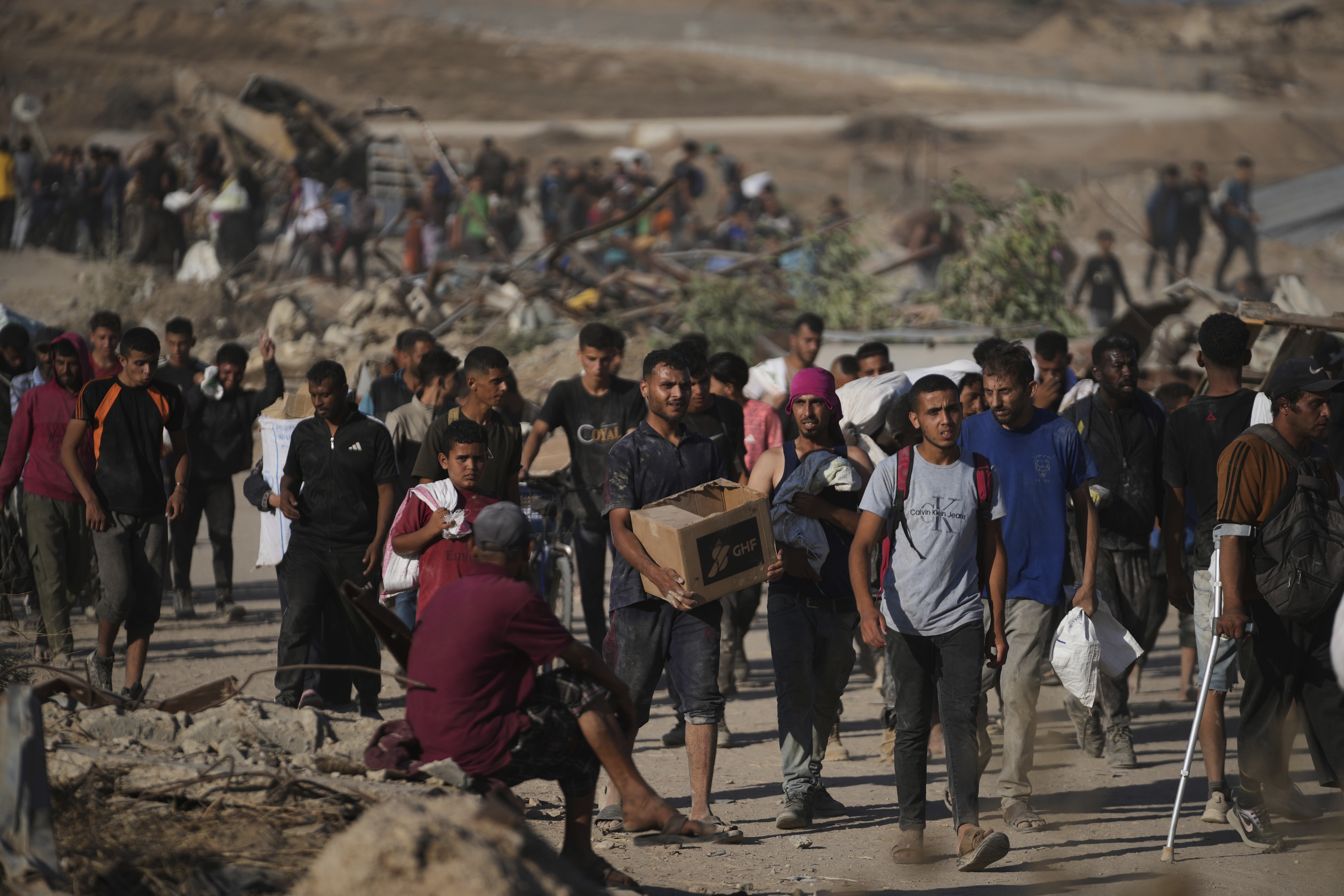 Palestinians carry food packages near a distribution site operated by the U.S.-backed Gaza Humanitarian Foundation in Khan Younis, southern Gaza Strip, Thursday. (AP Photo/Abdel Kareem Hana)