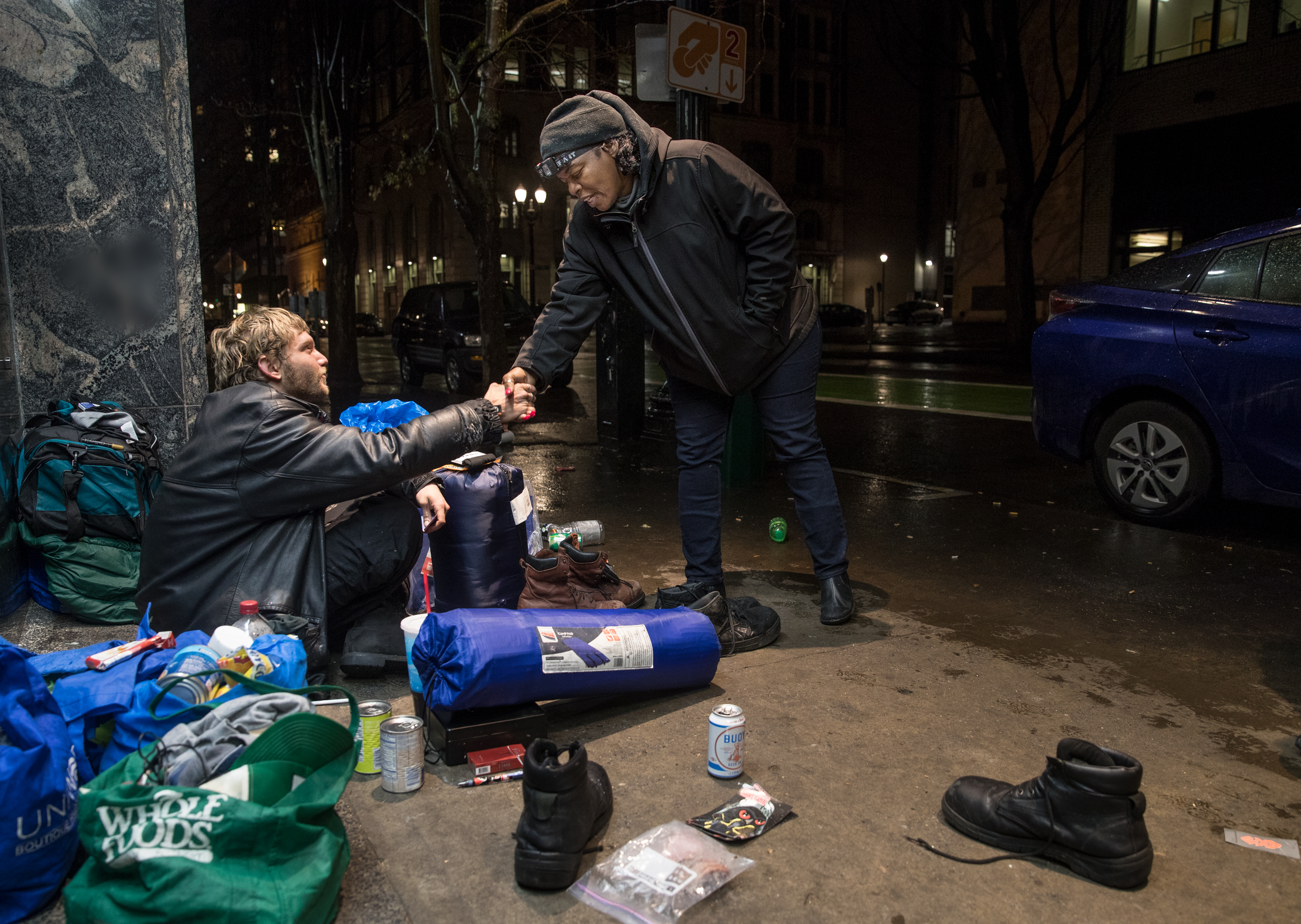 FILE: In this December 2018 photo provided by Multnomah County, a surveyor talks with a man on the street as homeless service providers delivered tarps, gloves and other winter items to people.