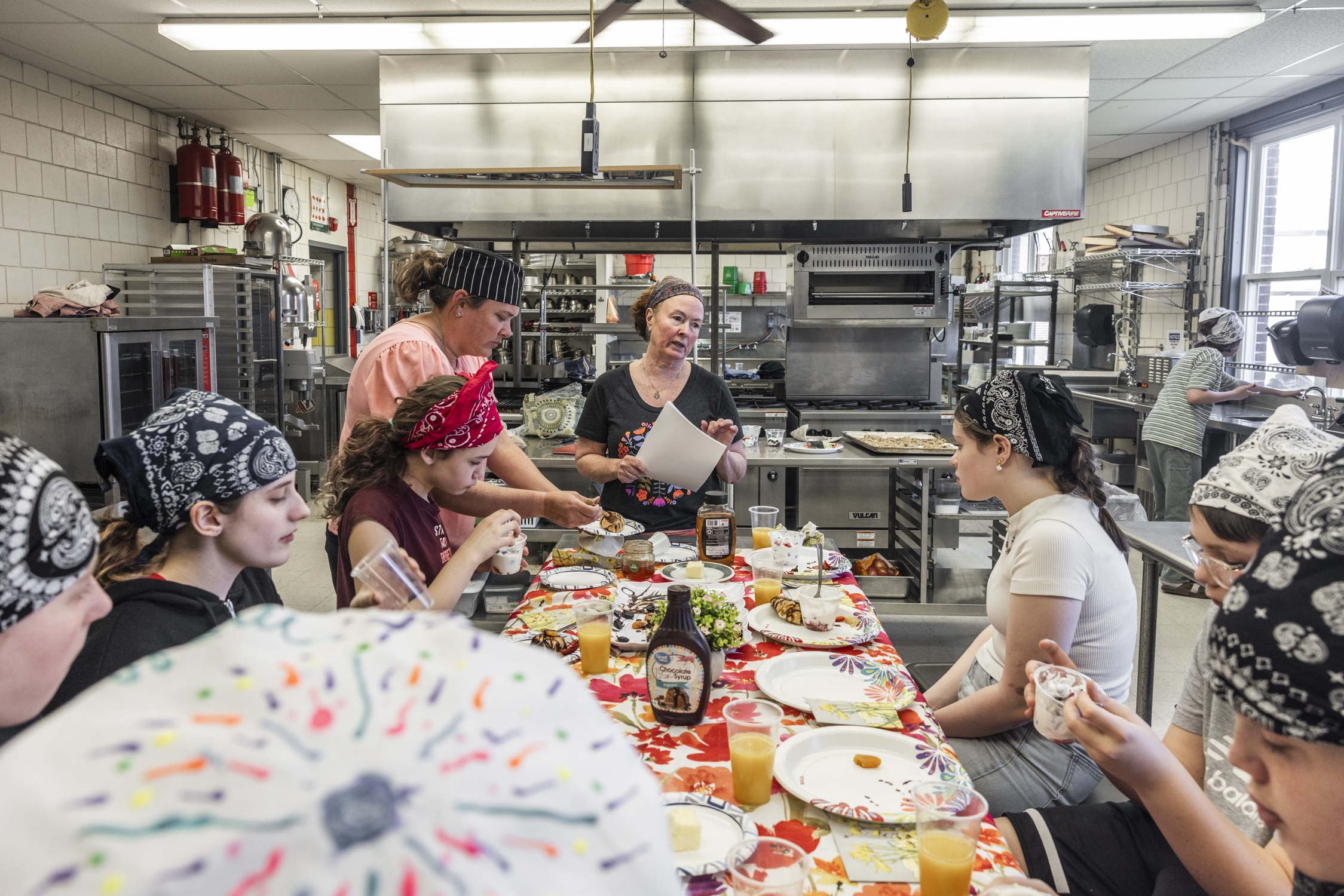 Retired chef and cooking instructor Brenda Madden gathers students around a table to enjoy their creations from the afternoon’s lesson on French cuisine.