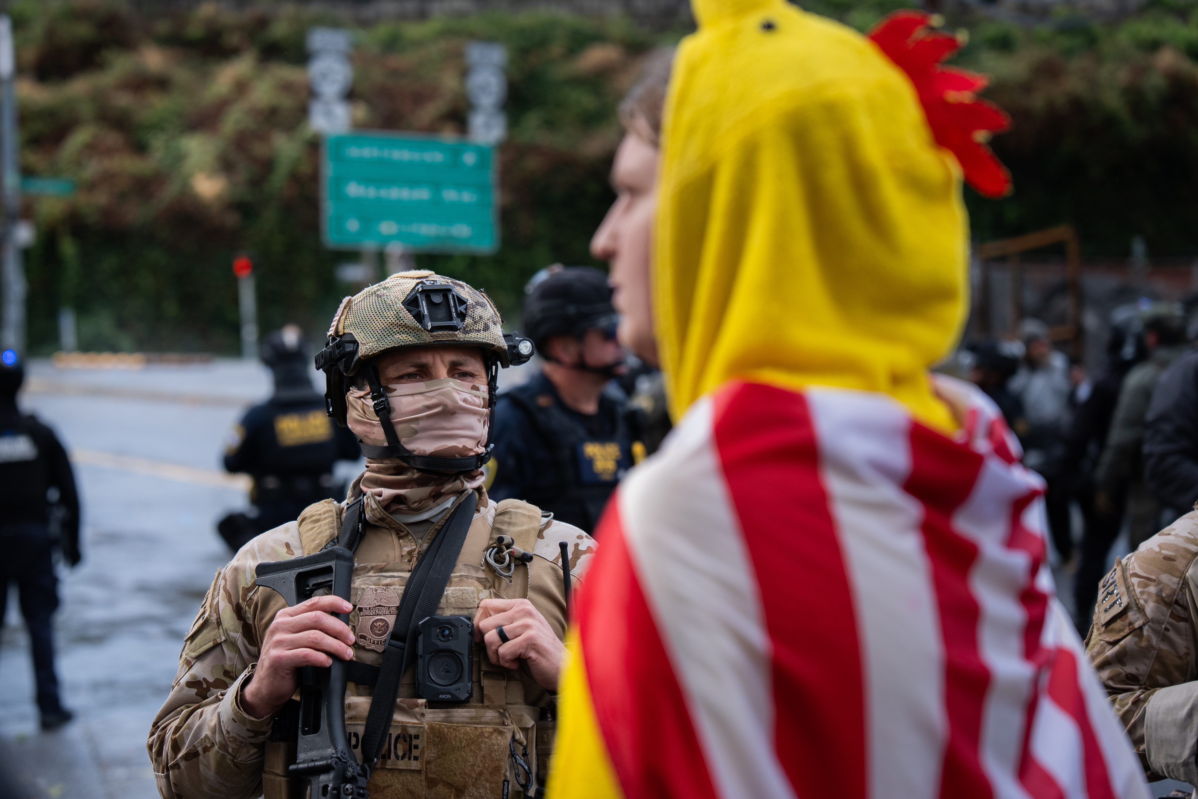 A federal agent and protesters stand in front of the Immigration and Customs Enforcement building in Portland, Ore., on Saturday, Oct. 25, 2025. A crowd of about 100 gathered in front of the building to protest that afternoon.