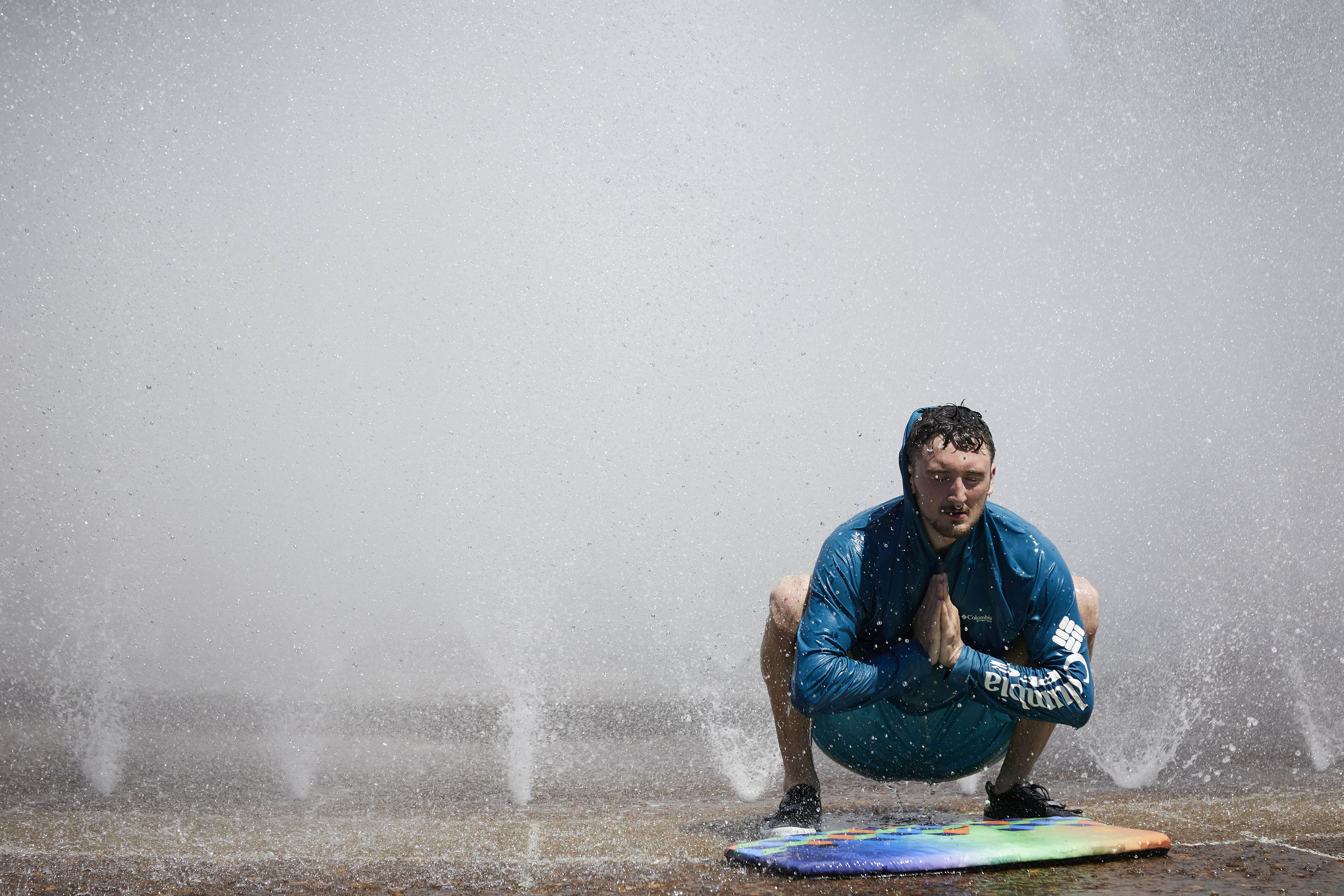 Jesse Moore cools off in the Salmon Street Springs fountain in Portland, Ore. on Tuesday, July 26, 2022.