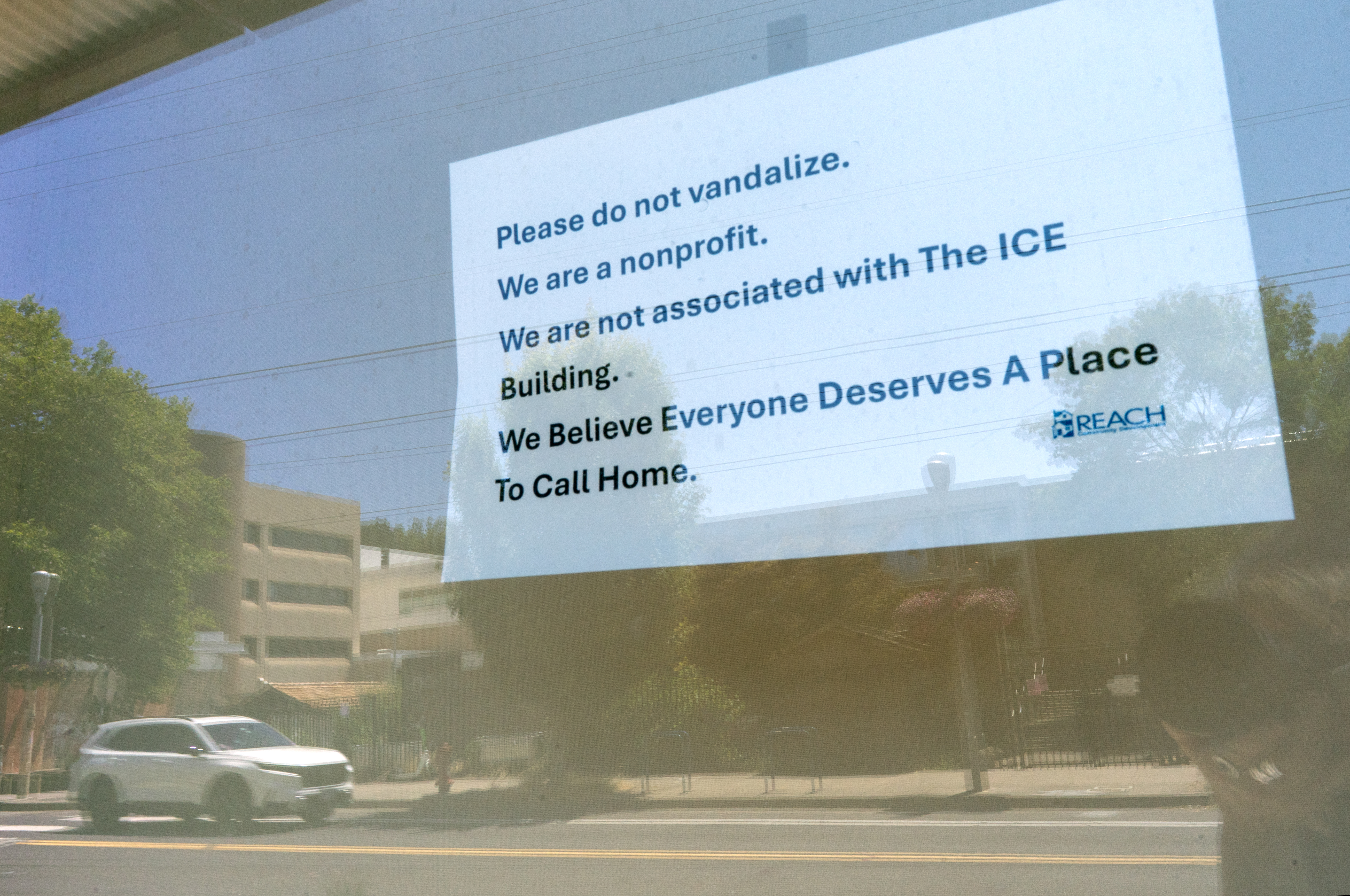 A sign on the window of the REACH Community Development offices in June 2025. The office is housed in the Gray’s Landing building, located kitty-corner from the U.S. Immigration and Customs Enforcement building in Portland. 