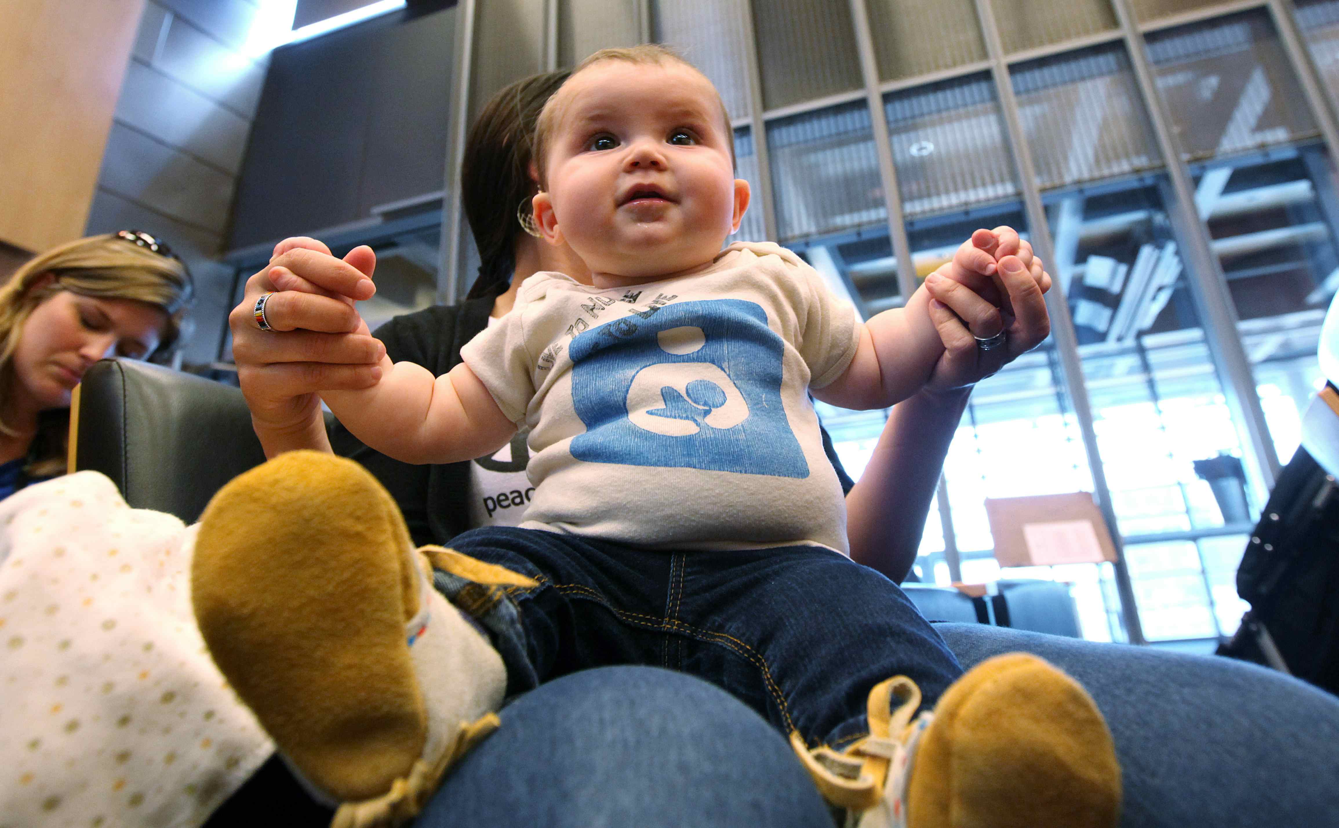 Johanna Goldhammer, 6 months, sits on the lap of her mother, Camie Goldhammer, chairman of the Native American Breastfeeding Coalition, as they listen to others testify about breastfeeding before the Seattle City Council Monday, April 9, 2012, in Seattle.