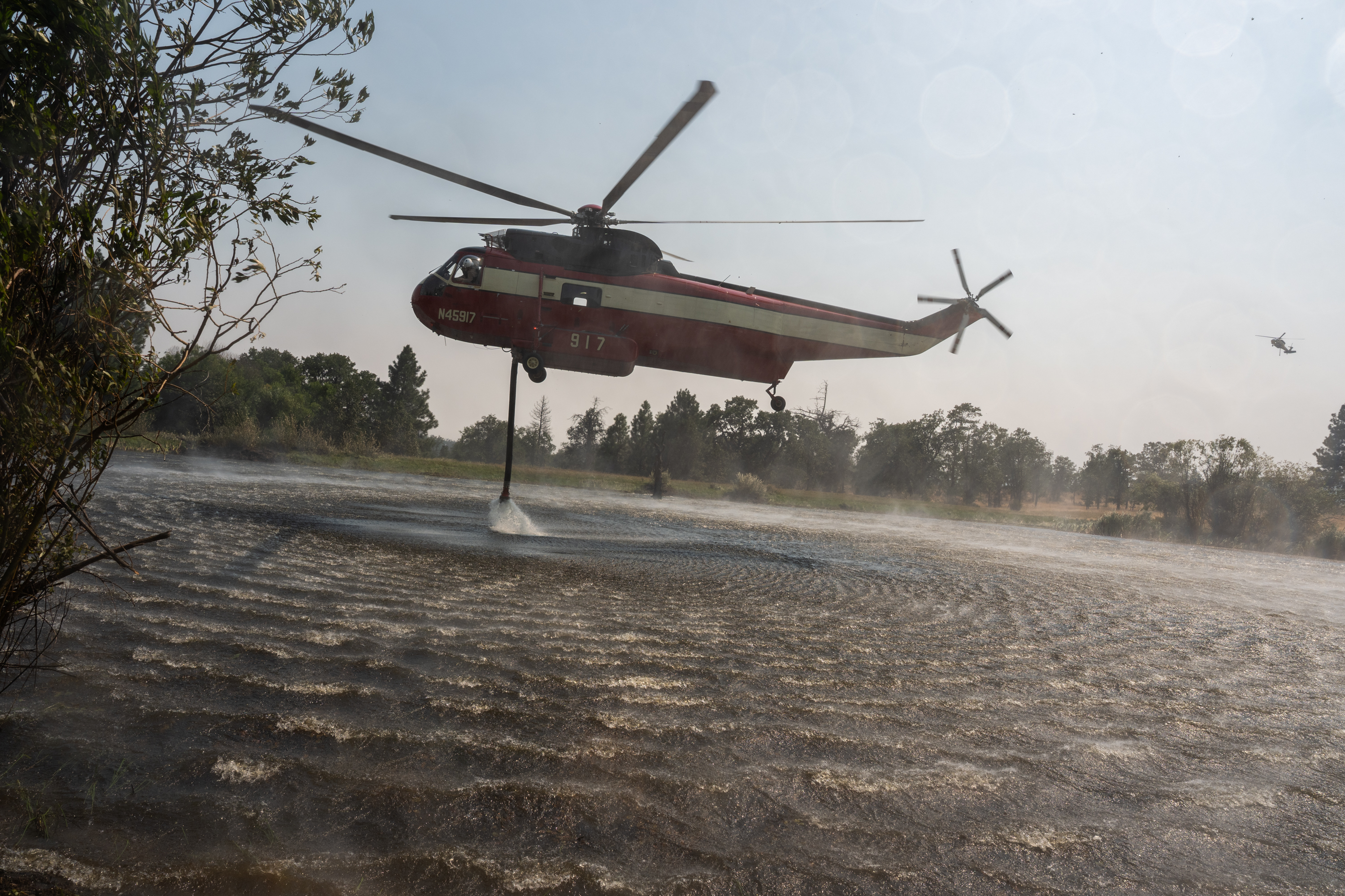 A firefighting helicopter refills water from a pond west of Friend, Ore., as crews battle the Grasshopper Fire, seen during a tour of the wildfire on Aug 3, 2026.