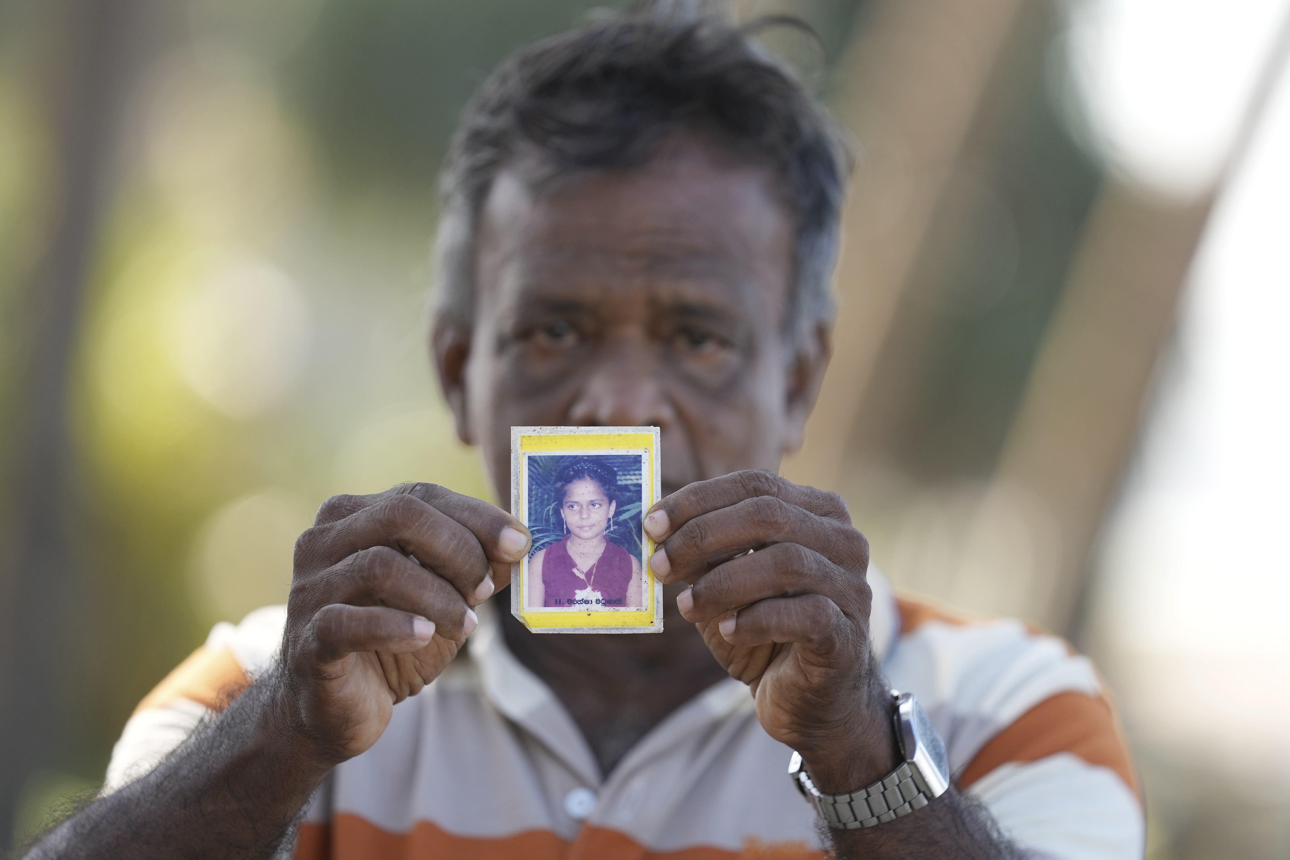Dayaratne Halambage shows a portrait of his daughter who died during the 2004 Indian Ocean tsunami at a memorial of the 20th anniversary of the calamity in Peraliya, Sri Lanka, Thursday, Dec. 26, 2024.