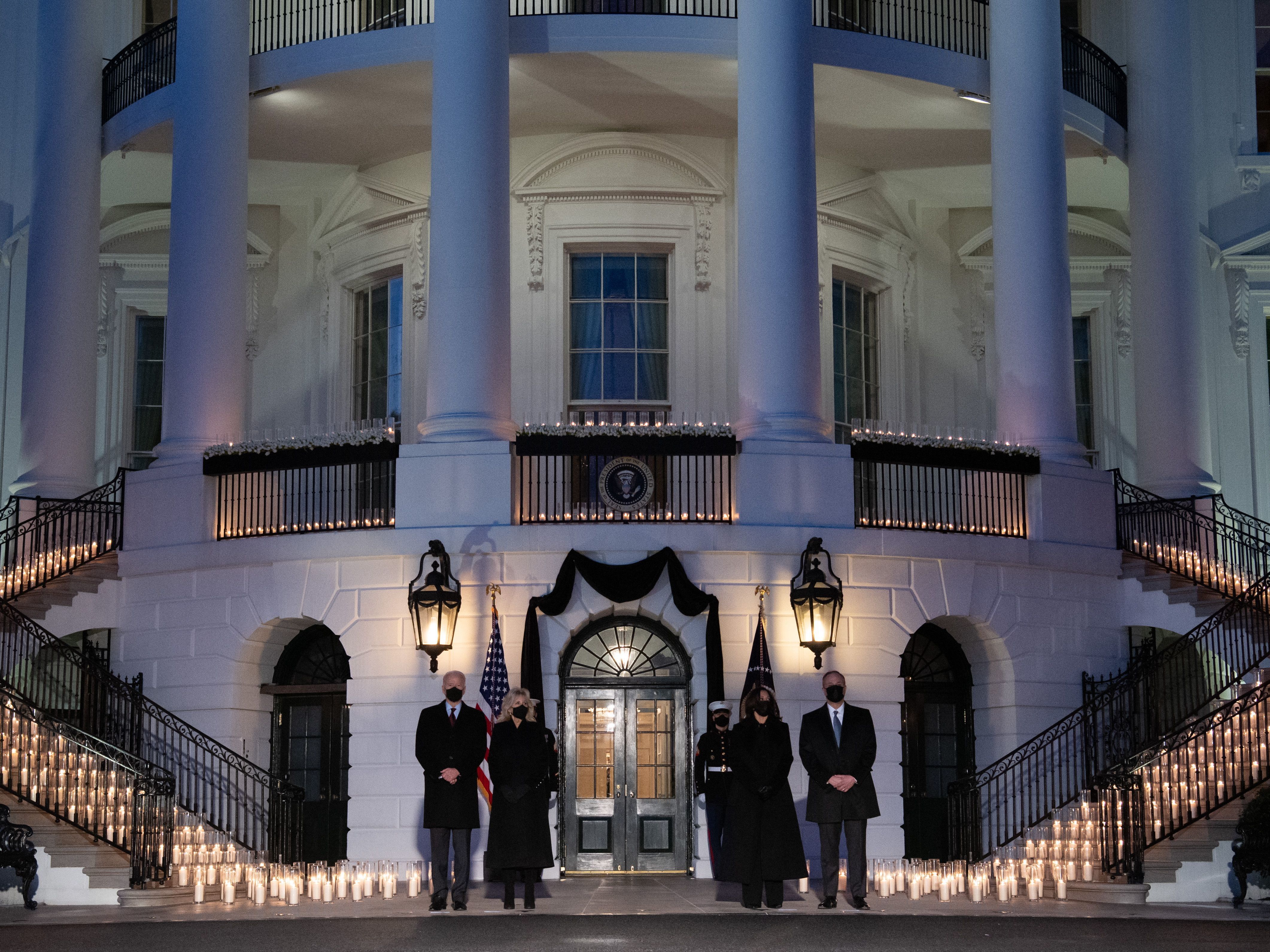 L-R: President Joe Biden, first lady Jill Biden, Vice President Kamala Harris and Doug Emhoff, hold a moment of silence and candelight ceremony in honor of those who lost their lives to the coronavirus outside the White House on Monday evening.