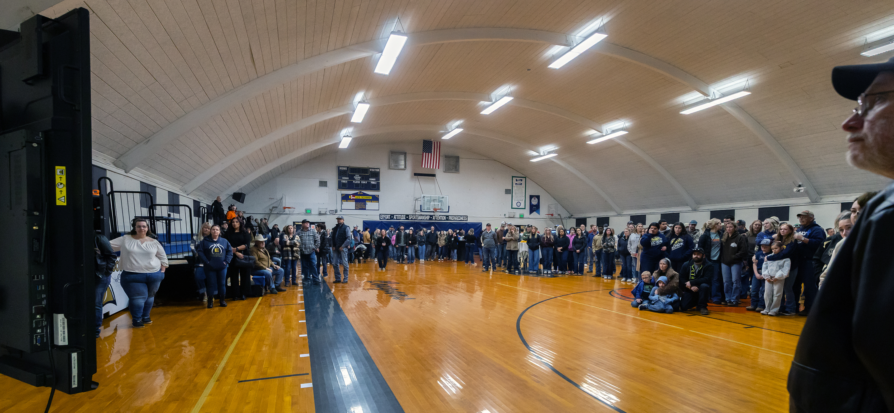 Around 100 people fill the old gymnasium watching a slide show and listening to music.