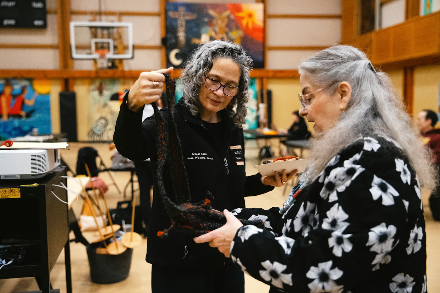 Susan Pavel, left, with Coast Salish Wool Weaving Center, looks at a purse created by student Sue Dixon, right, on Saturday, March 7, 2026, during a weaving class at the Don Hatch Youth Center in Tulalip.