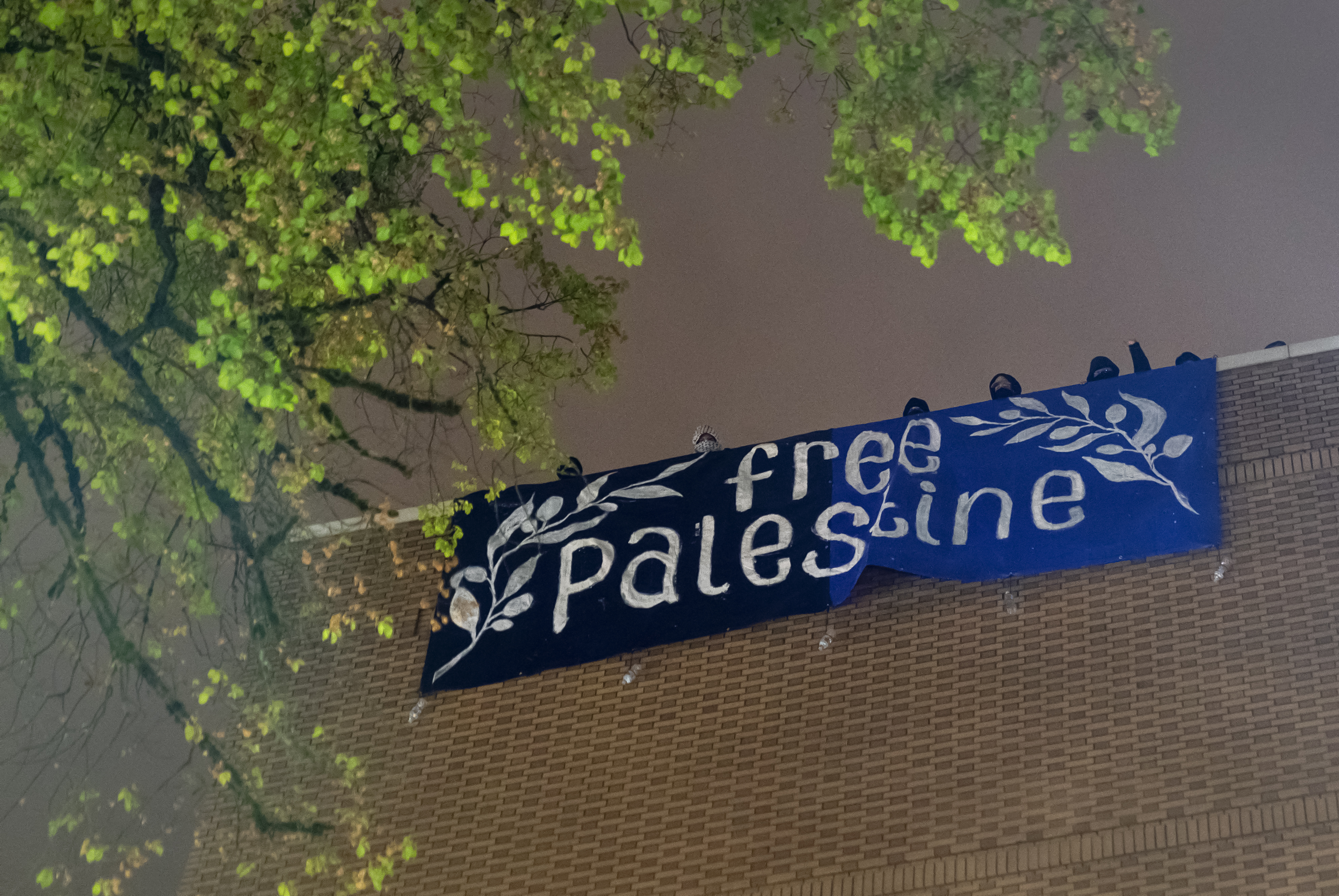 FILE: A large sign is unfurled from the roof of the building while spectators cheer, as the occupation continued at Portland State University’s Branford Price Millar Library, May 1, 2024.