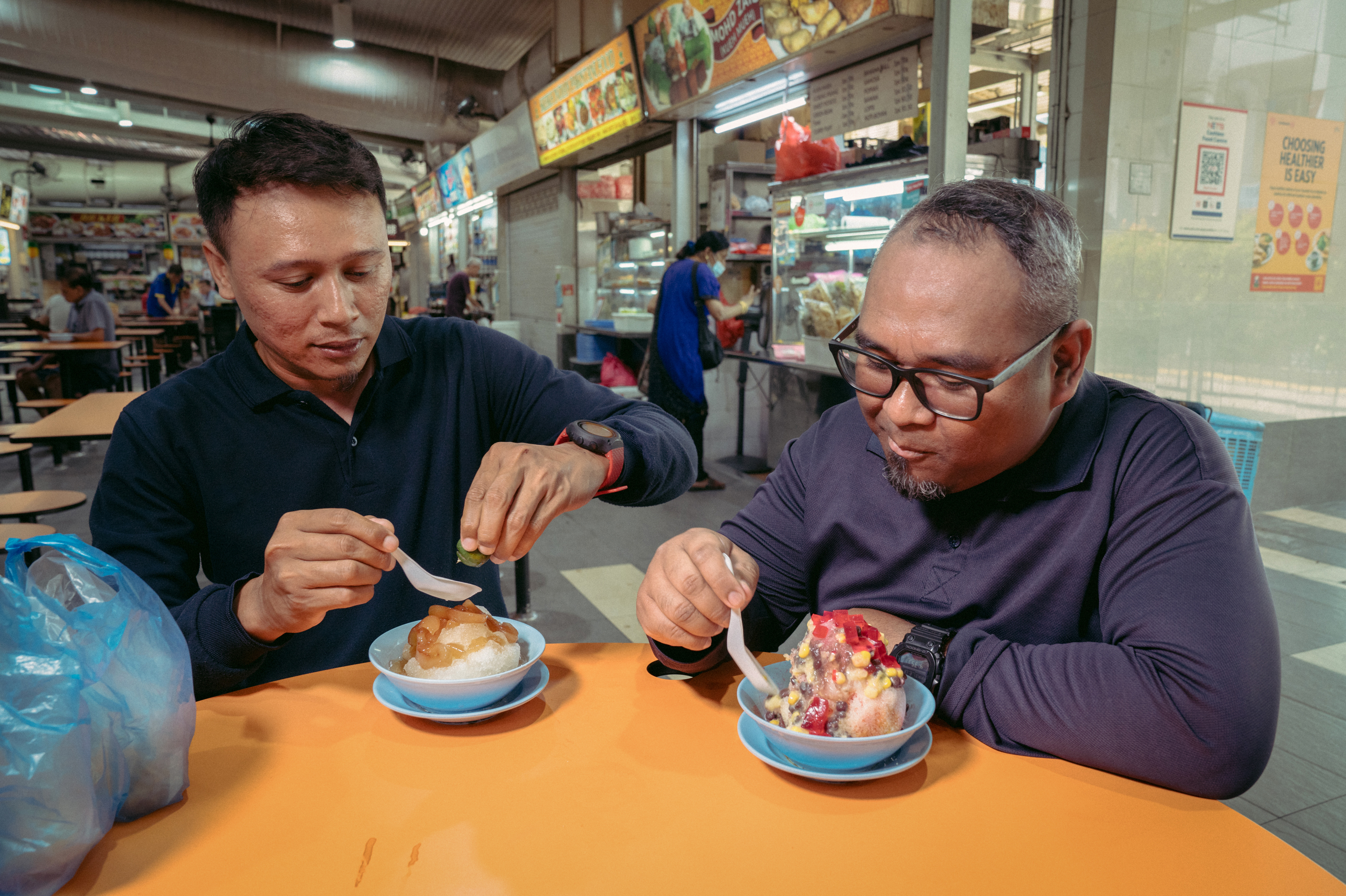 Muhammad Azreen (left) and Airul Hizen (right) enjoy sea coconut ice jelly and ice kachang from Jin Jin dessert at ABC Brickworks Market & Food Center. When bought at one of the large food courts in the country, called hawker centers, the dessert is generally an affordable way to cool down at 2 - 4 SGD ($1.48 to $2.96).