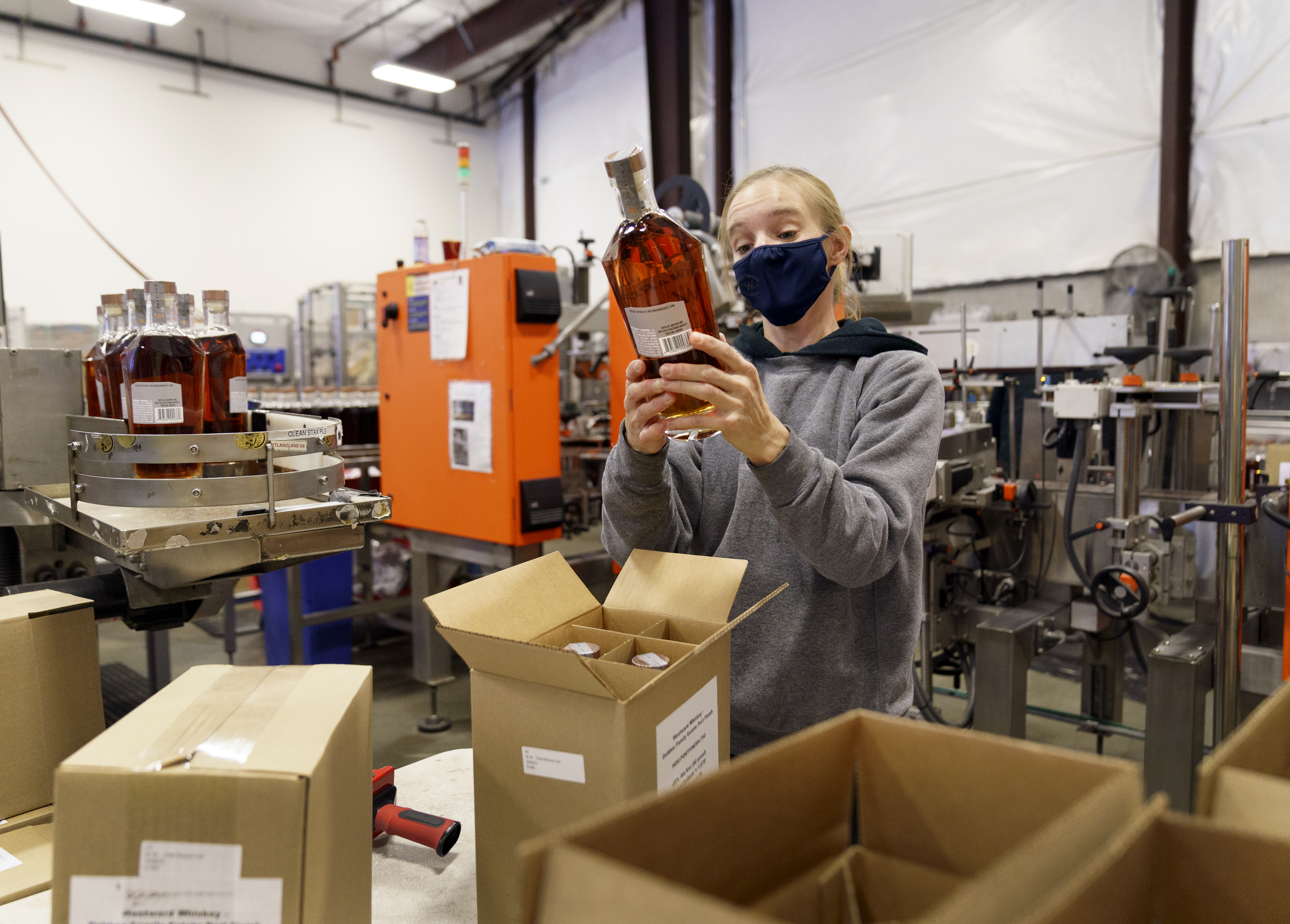 Westward Whiskey employee Alyssa McMillen checks a label while packaging a 750ml bottle at the Southeast Portland distillery in Oct. 8, 2021. The company has experienced delays in bottle deliveries from Mexico.