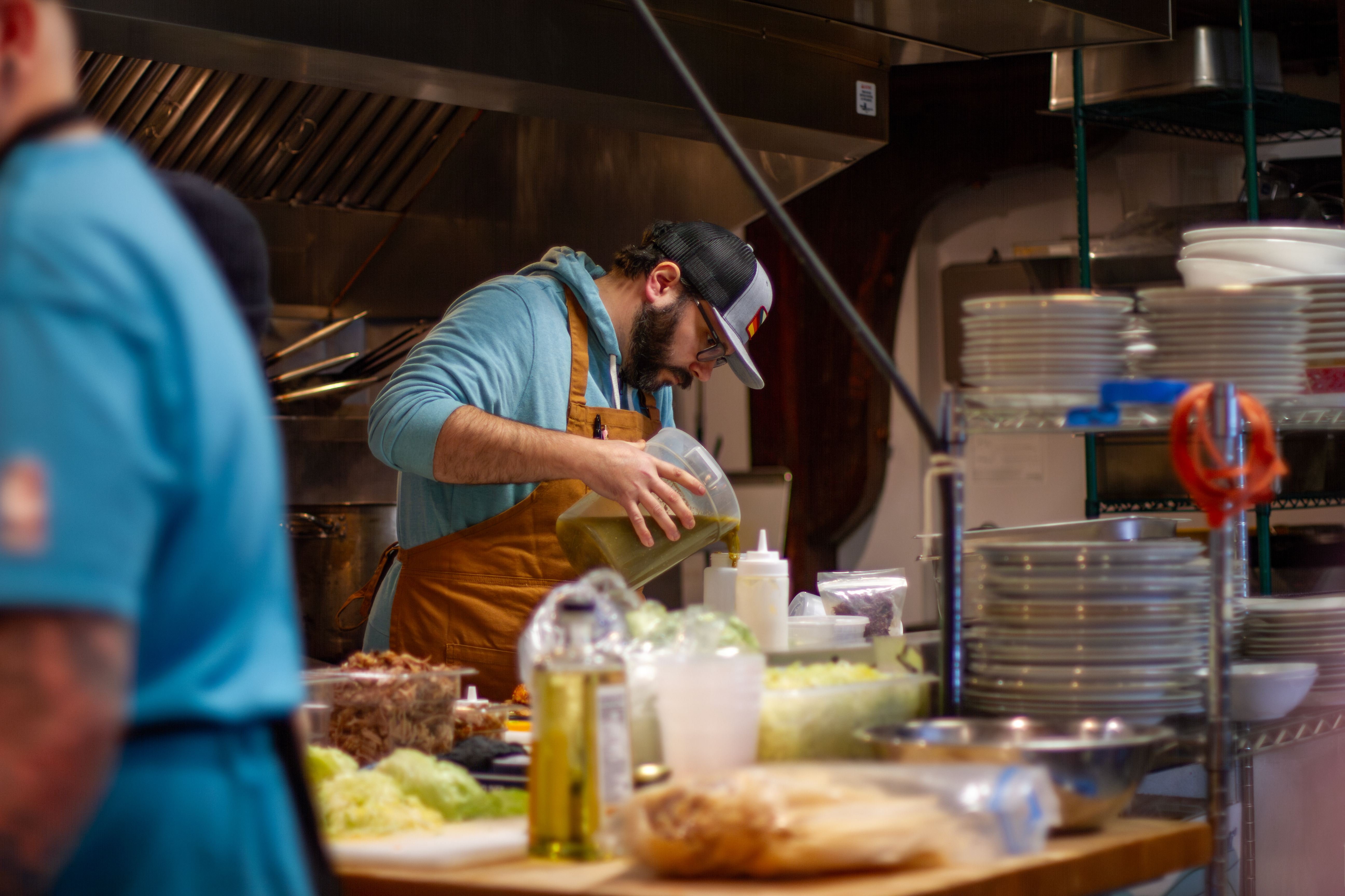 Steven Stimek, chef de cuisine for Javelina, pours verde sauce into bottles, which will be used to drizzle sauce on braised wild rabbit legs.