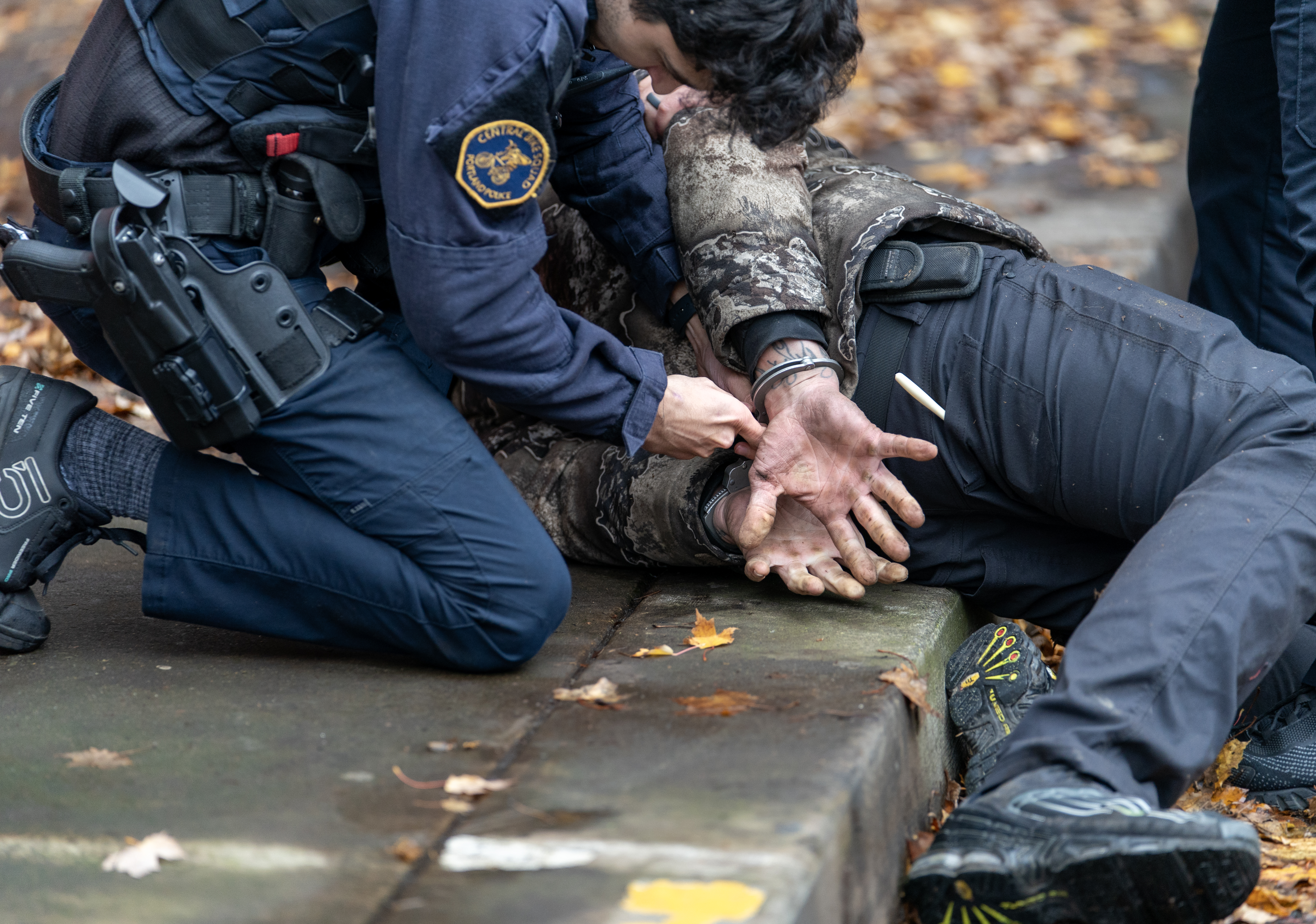 Portland Police Central Bike Squad officer Donny Mathew cuffs a man arrested while in downtown Portland, Ore., Nov. 15, 2023. 