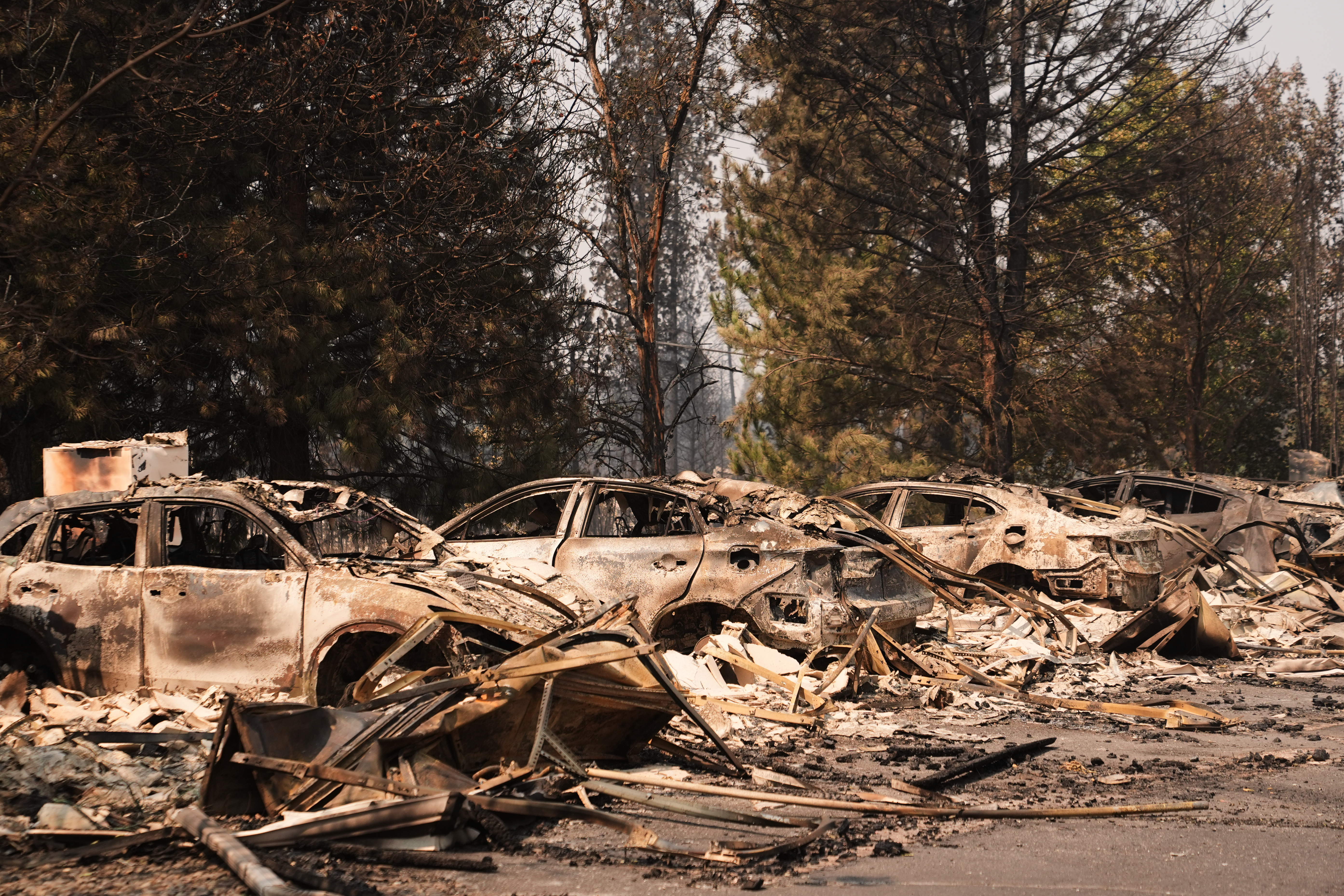A line of burned cars sit in a parking lot Tuesday, Aug. 4, 2026, after a wildfire hit the northern part of Spokane, Wash.