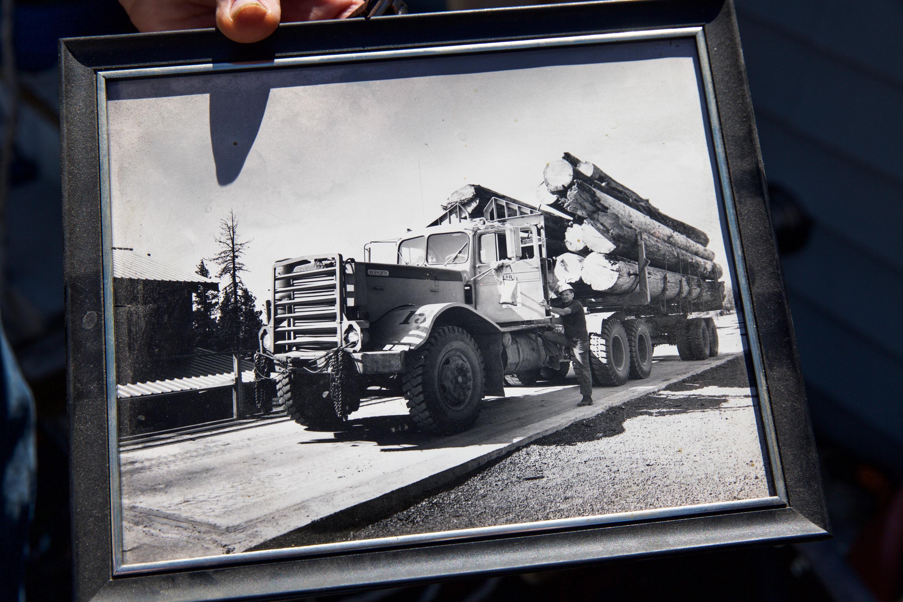 Otis Cody holds a photo of his father, Ray Cody, next to an old logging truck from the former company town of Kinzua at his home in Fossil, Ore., Tuesday, June 4, 2019.
