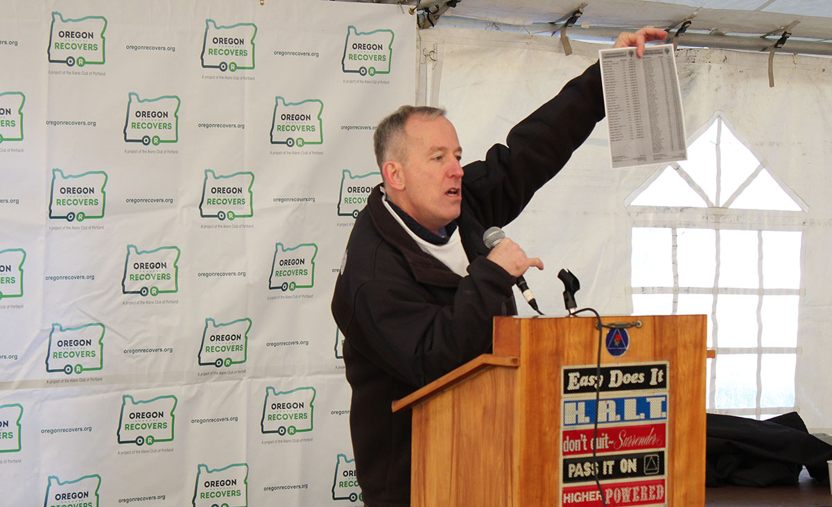 Person standing at lectern holds up a piece of paper to an unseen crowd