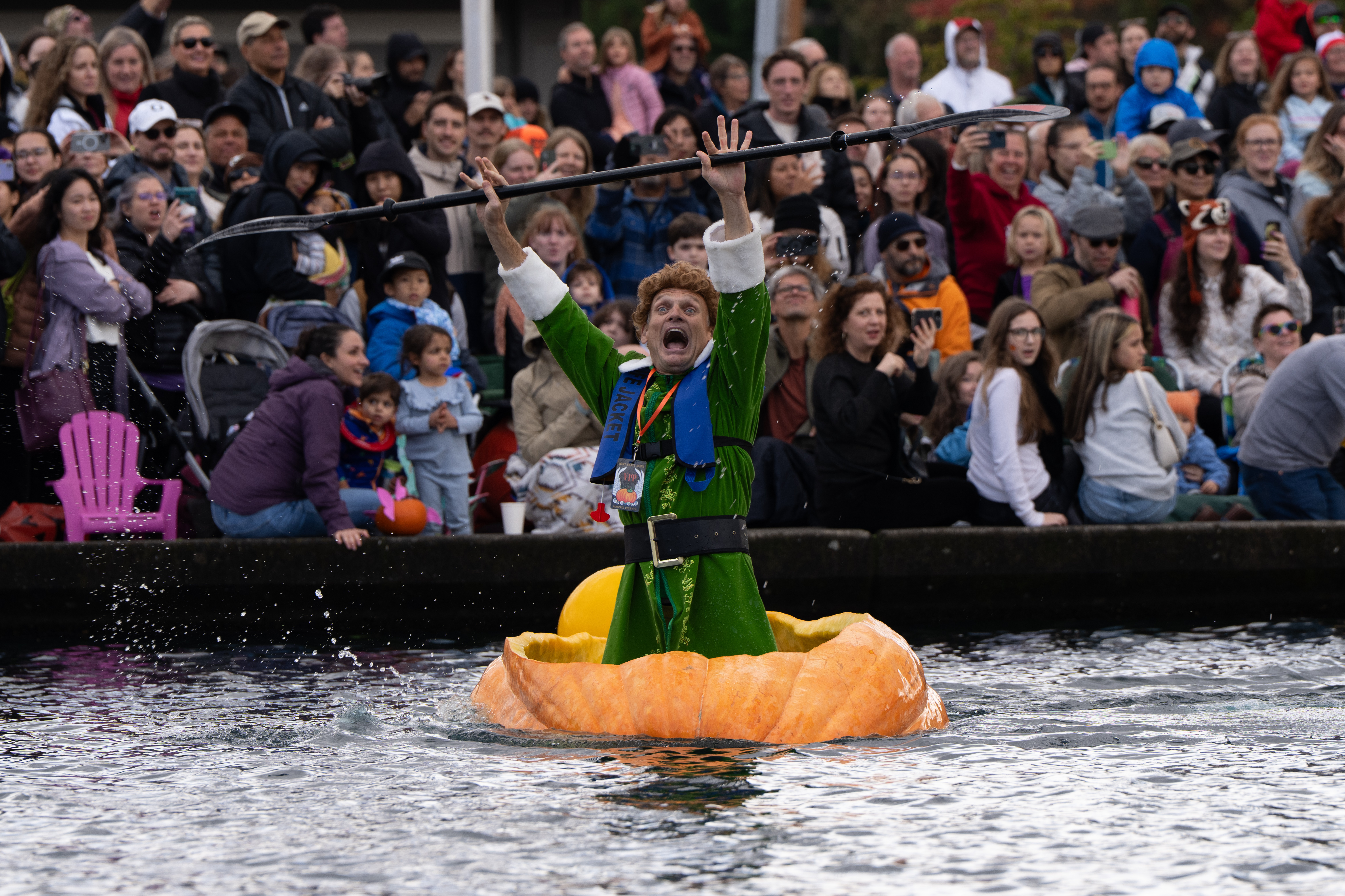 Gary Kristensen, dressed up as the character Buddy from the holiday movie "Elf," celebrates after winning a race during the West Coast Giant Pumpkin Regatta on Sunday, Oct. 19, 2025, in Tualatin, Ore.