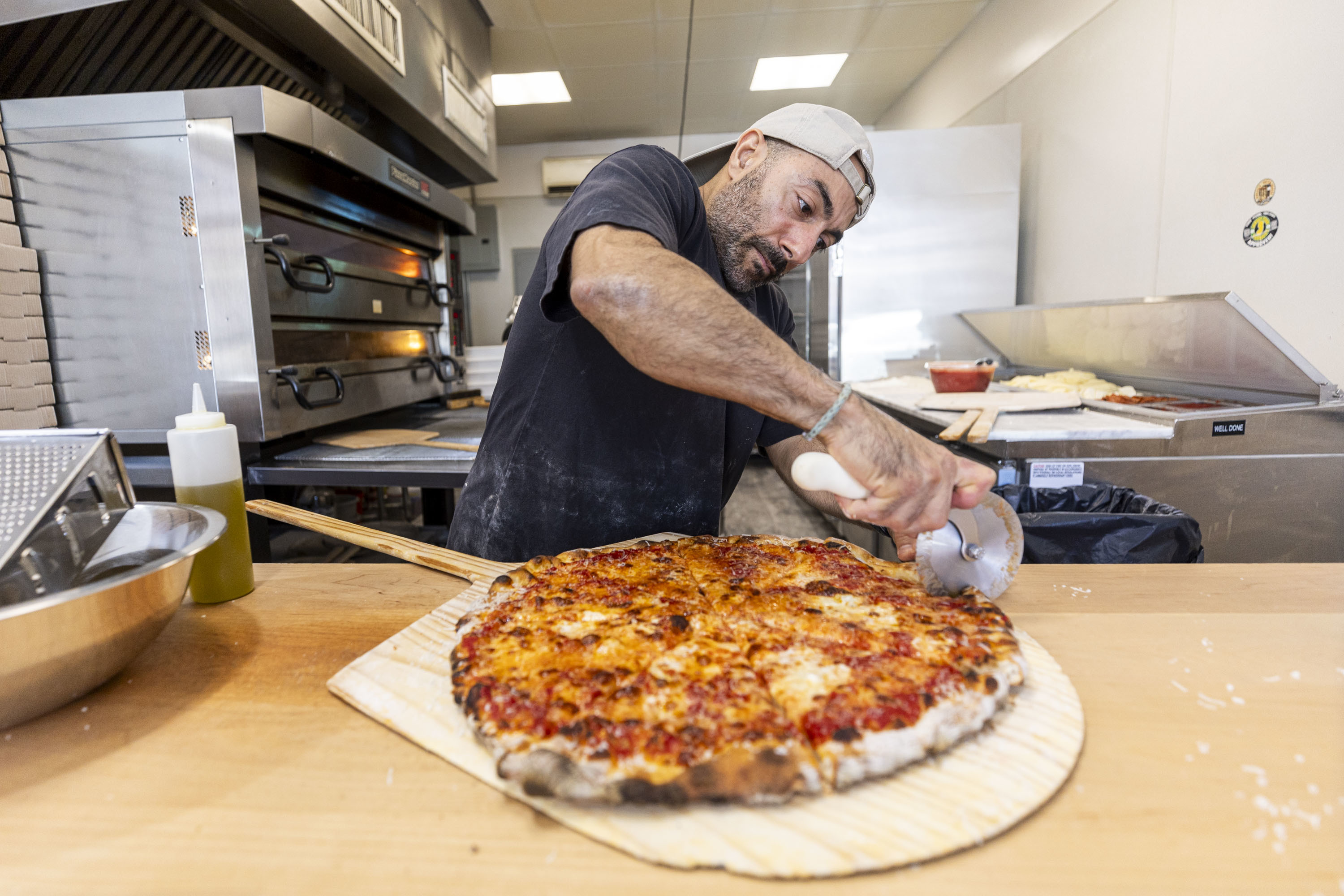 Speer Madanat, of West Chester, Pa., Owner of Pizza West Chester, slices the pizza into eight slices at his pizza shop in West Chester, Pa., on Tuesday, Sept., 3, 2024. .