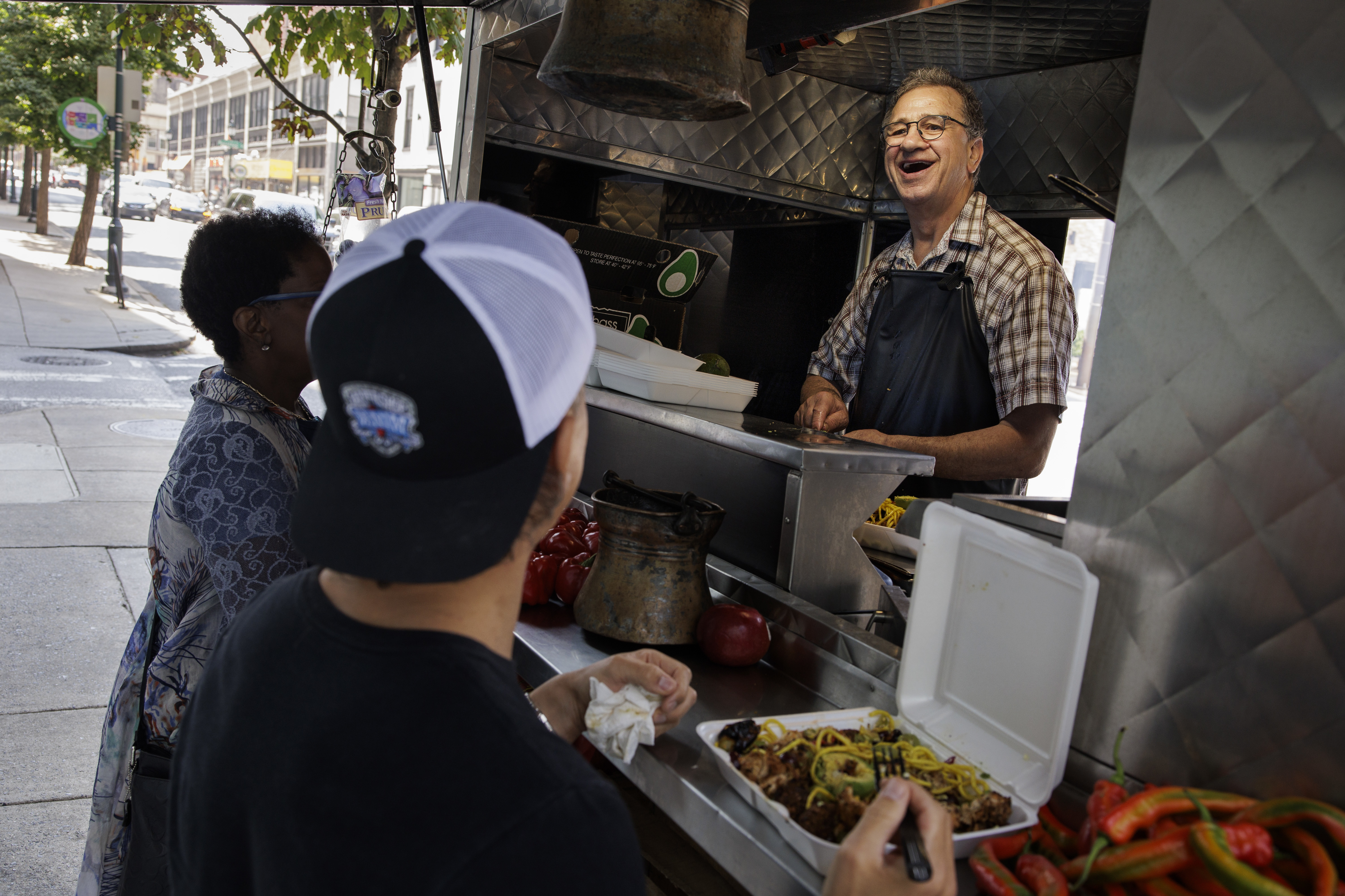 Christis “Kostas” Konstadinos laughs with regular customer Chris Cahill at the Octopus Cart on 20th Street near Market Street in Philadelphia on Tuesday, Sept. 3, 2024.